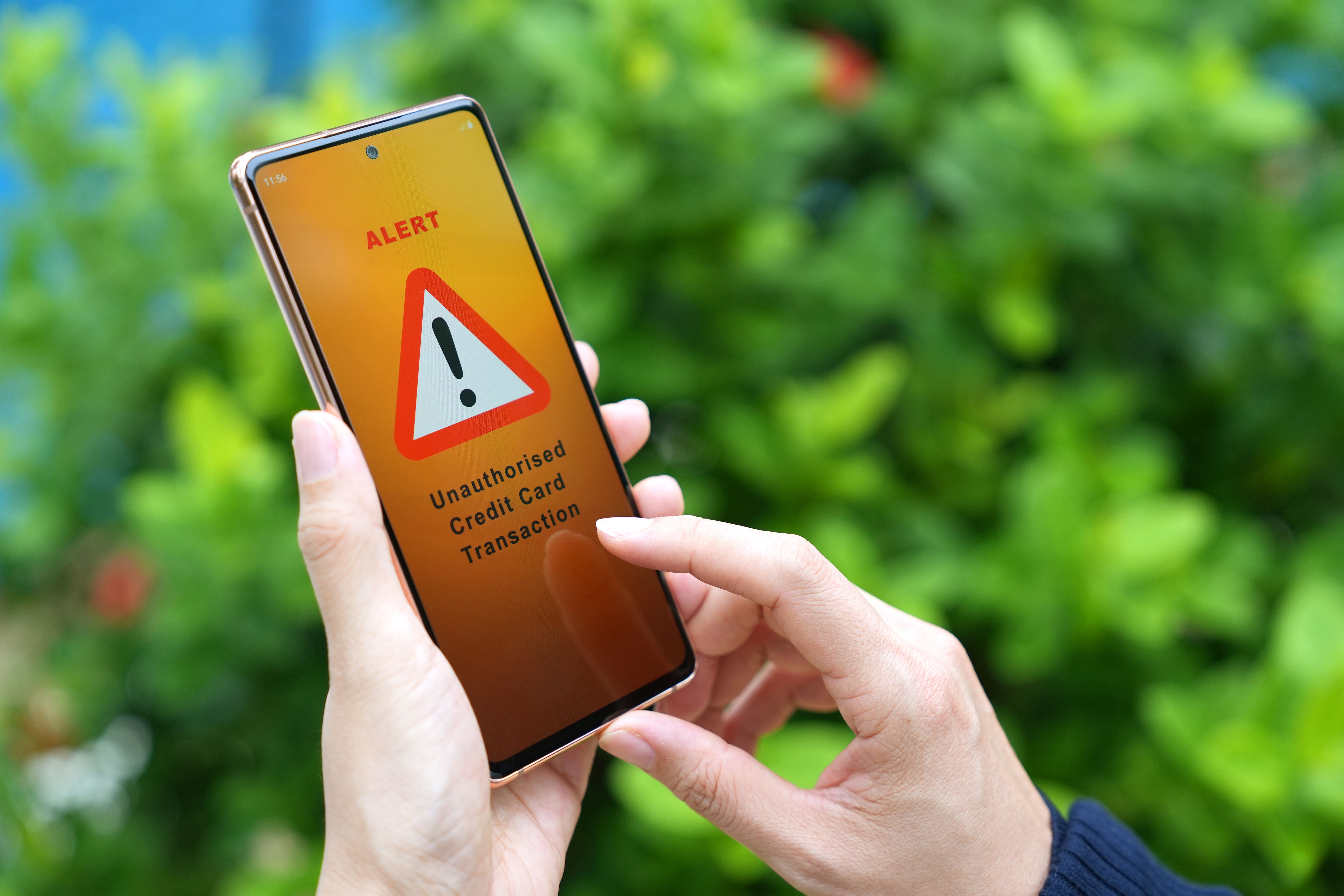 A woman receiving an alert message from bank regarding unauthorised credit card transaction on her smartphone. A woman receiving an alert message from bank regarding unauthorised credit card transaction on her smartphone.