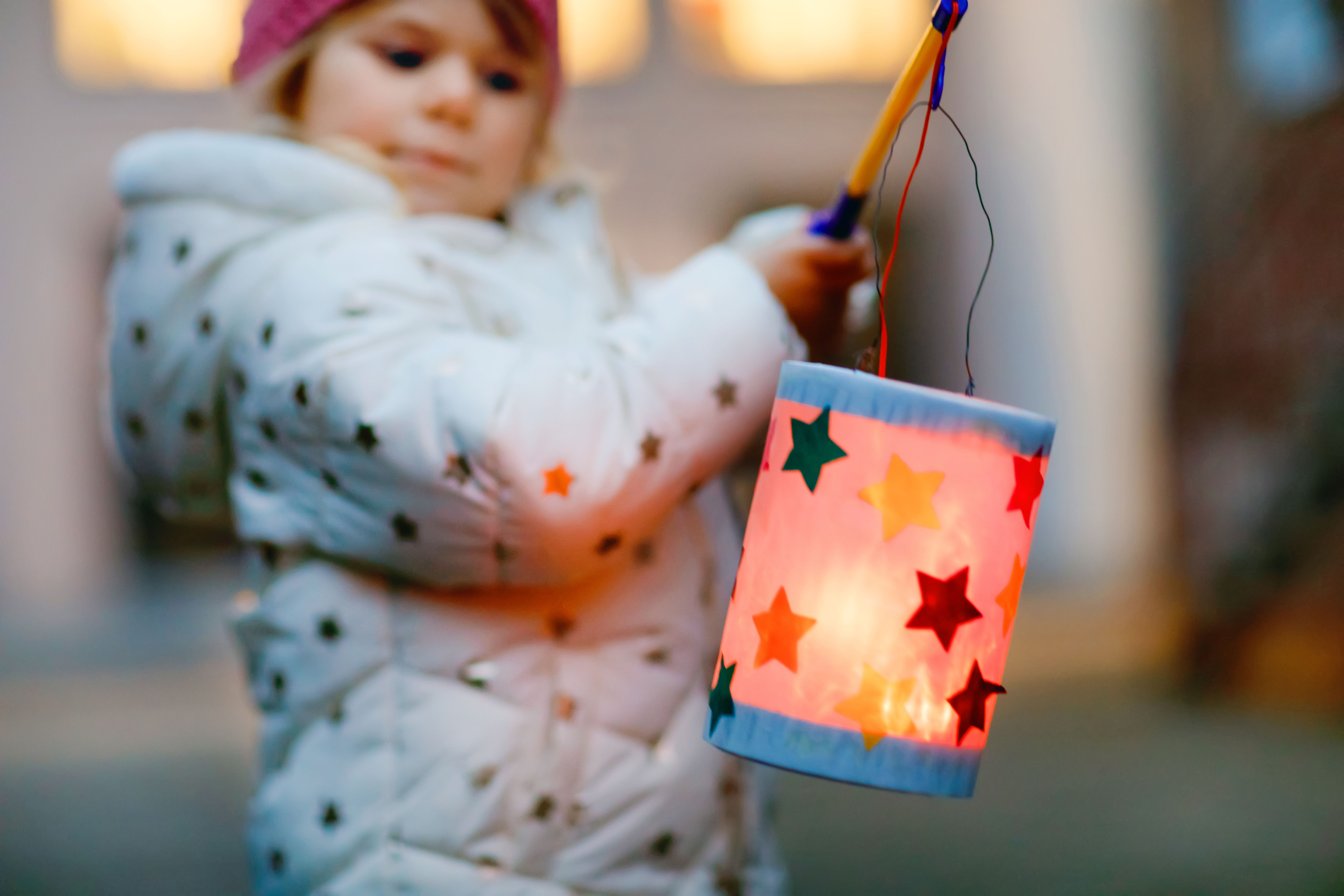 Close-up of little kid girl holding selfmade lanterns with candle for St. Martin procession. Healthy toddler child happy about children and family parade in kindergarten. German tradition Martinsumzug Close-up of little kid girl holding selfmade lanterns with candle for St. Martin procession. Healthy toddler child happy about children and family parade in kindergarten. German tradition Martinsumzug