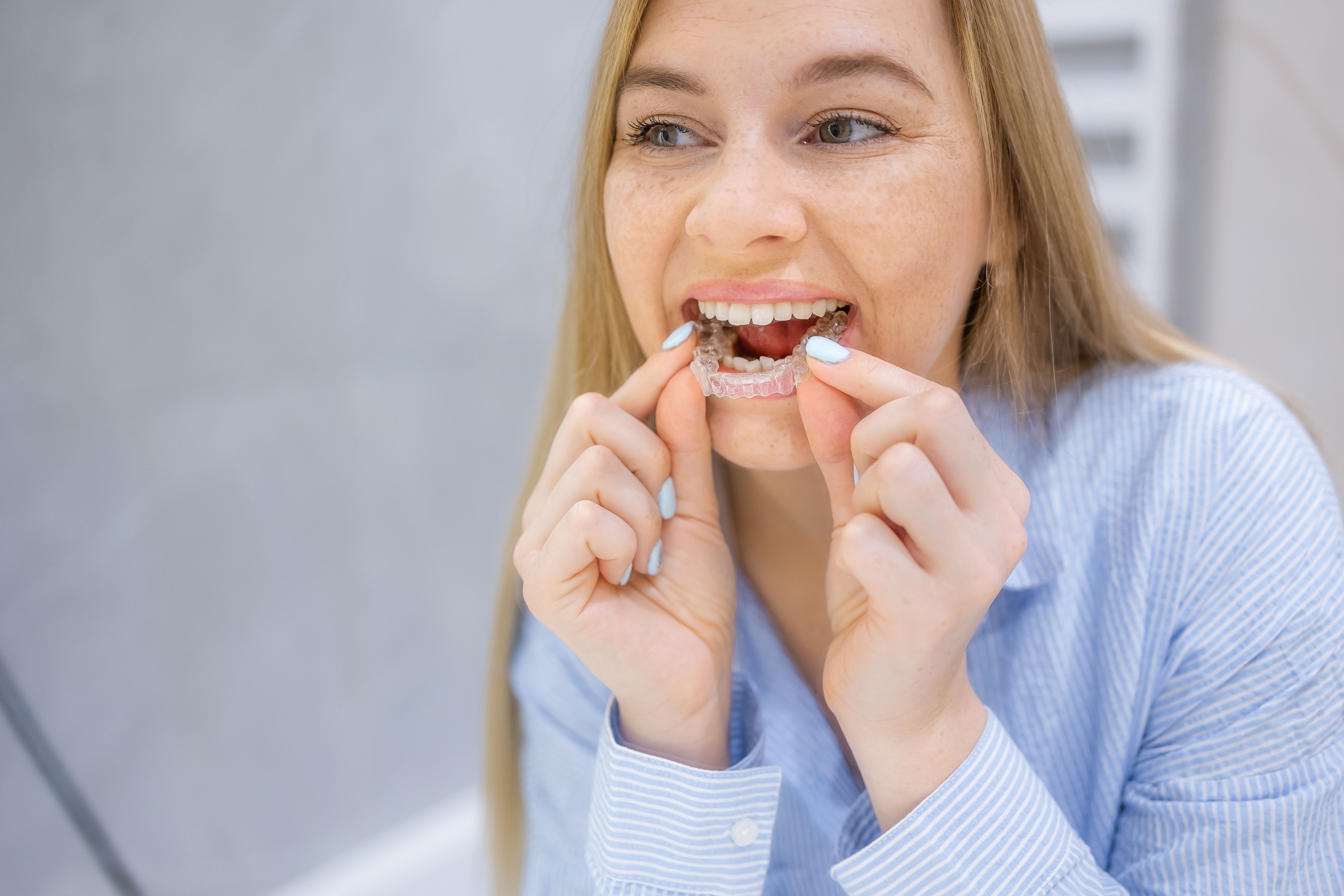 Mujer sonriente que usa alineador invisible para la corrección de dientes y el tratamiento ortodóncico