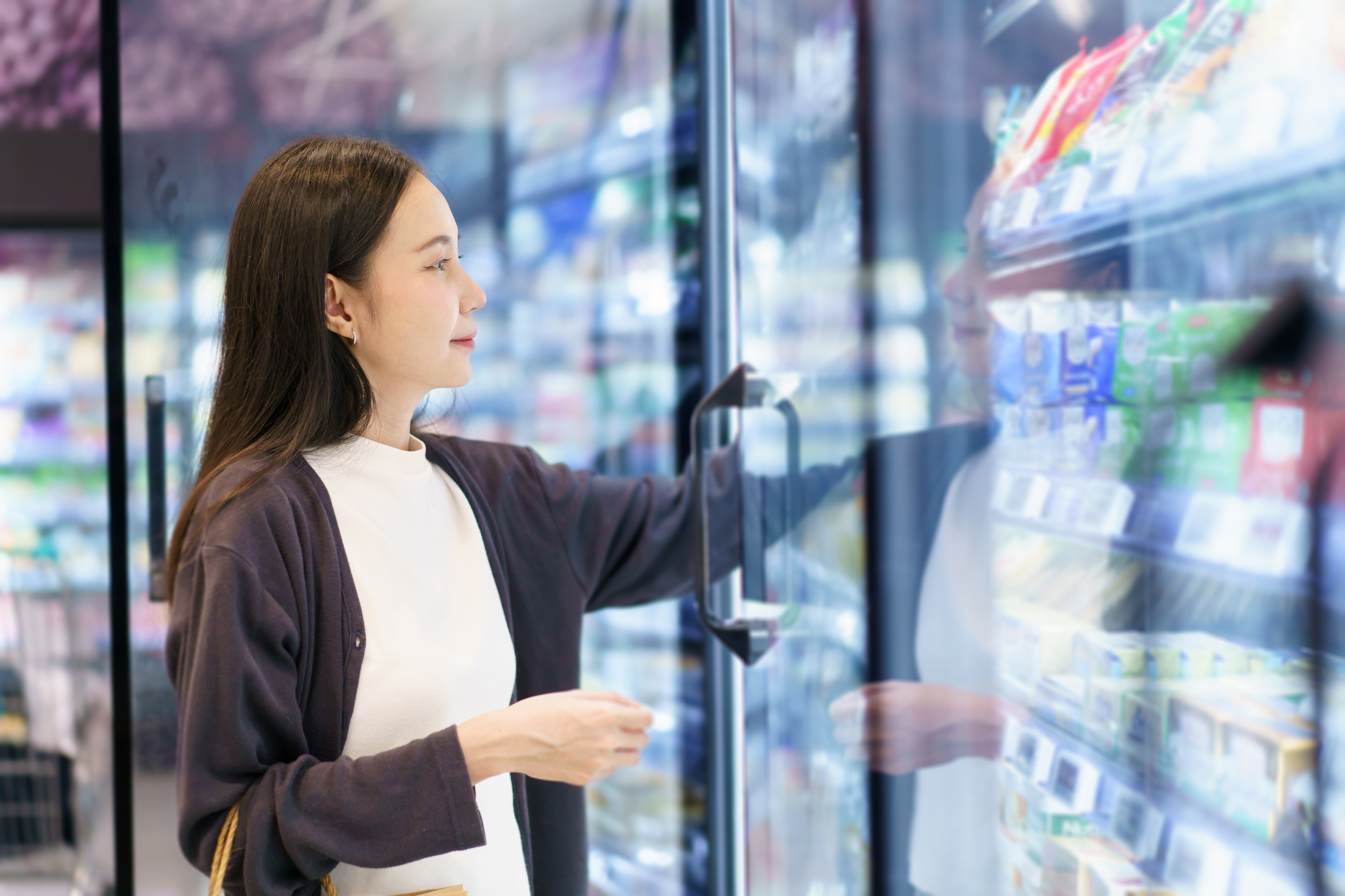 Frau wählt ein Milchprodukt im Supermarkt aus. Frau wählt ein Milchprodukt im Supermarkt aus.