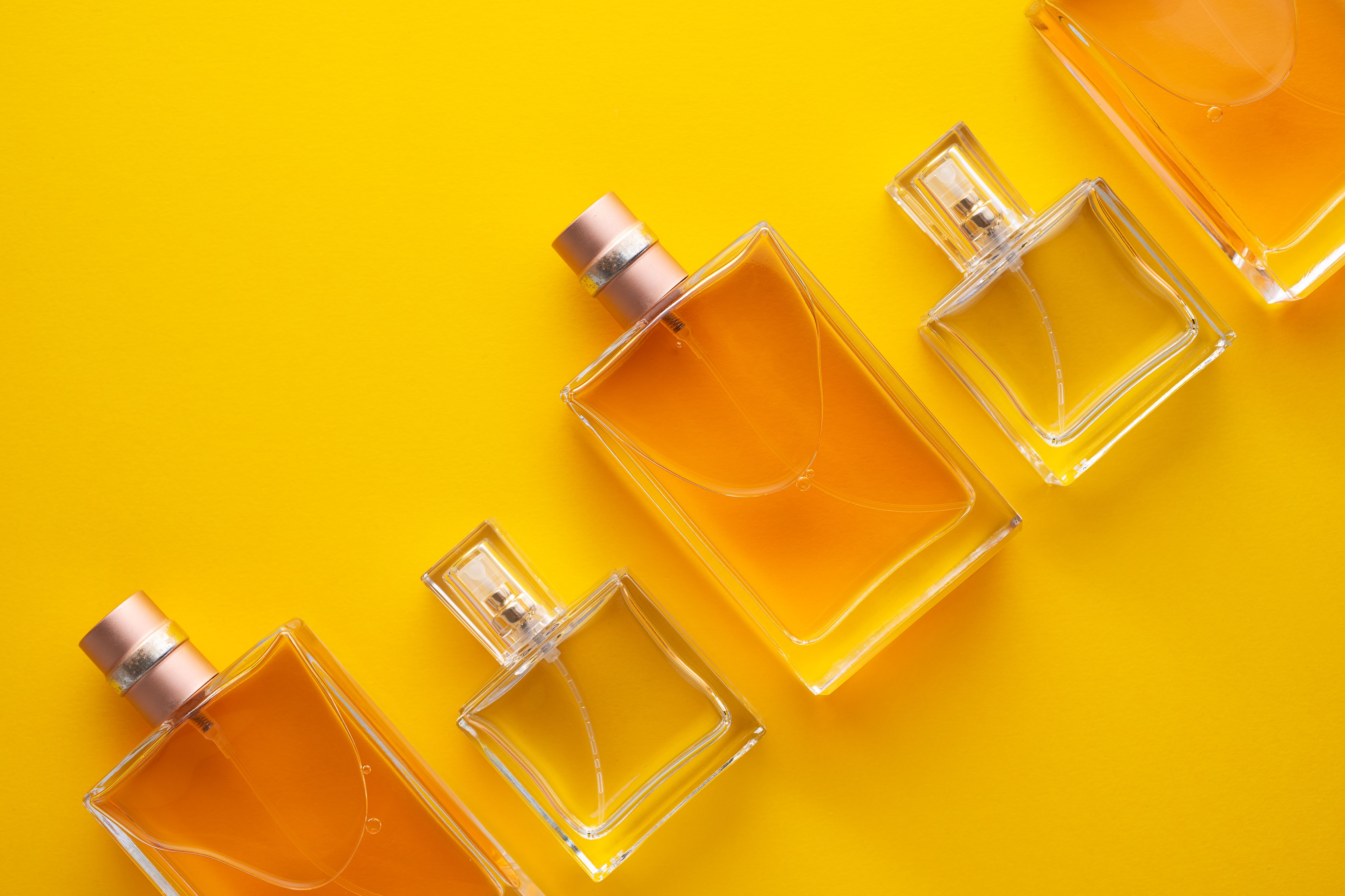 Close-Up Of Perfume Sprayers Against Yellow Background