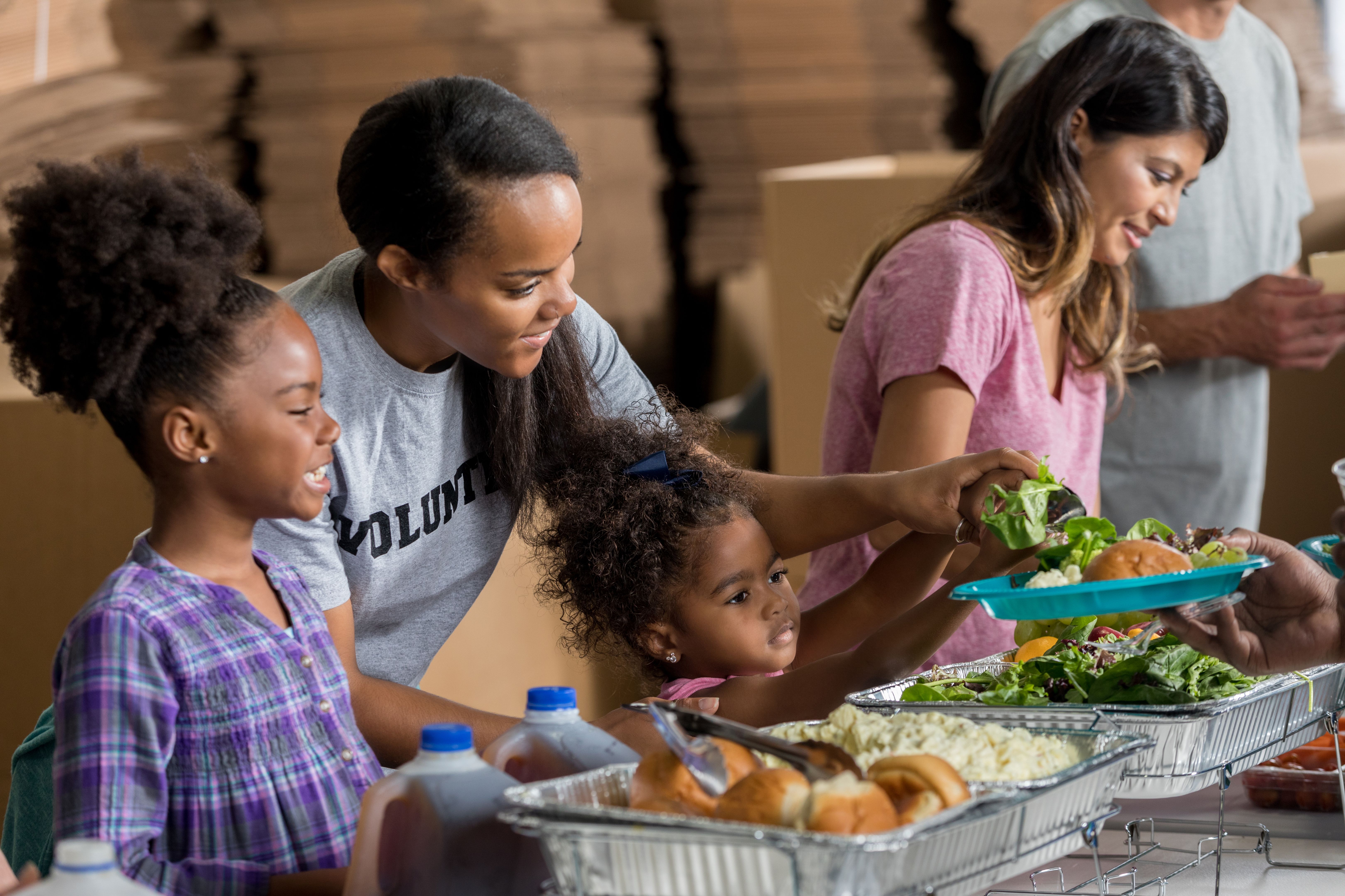 African American mom and daughters volunteer in soup kitchen African American mom and daughters volunteer in soup kitchen