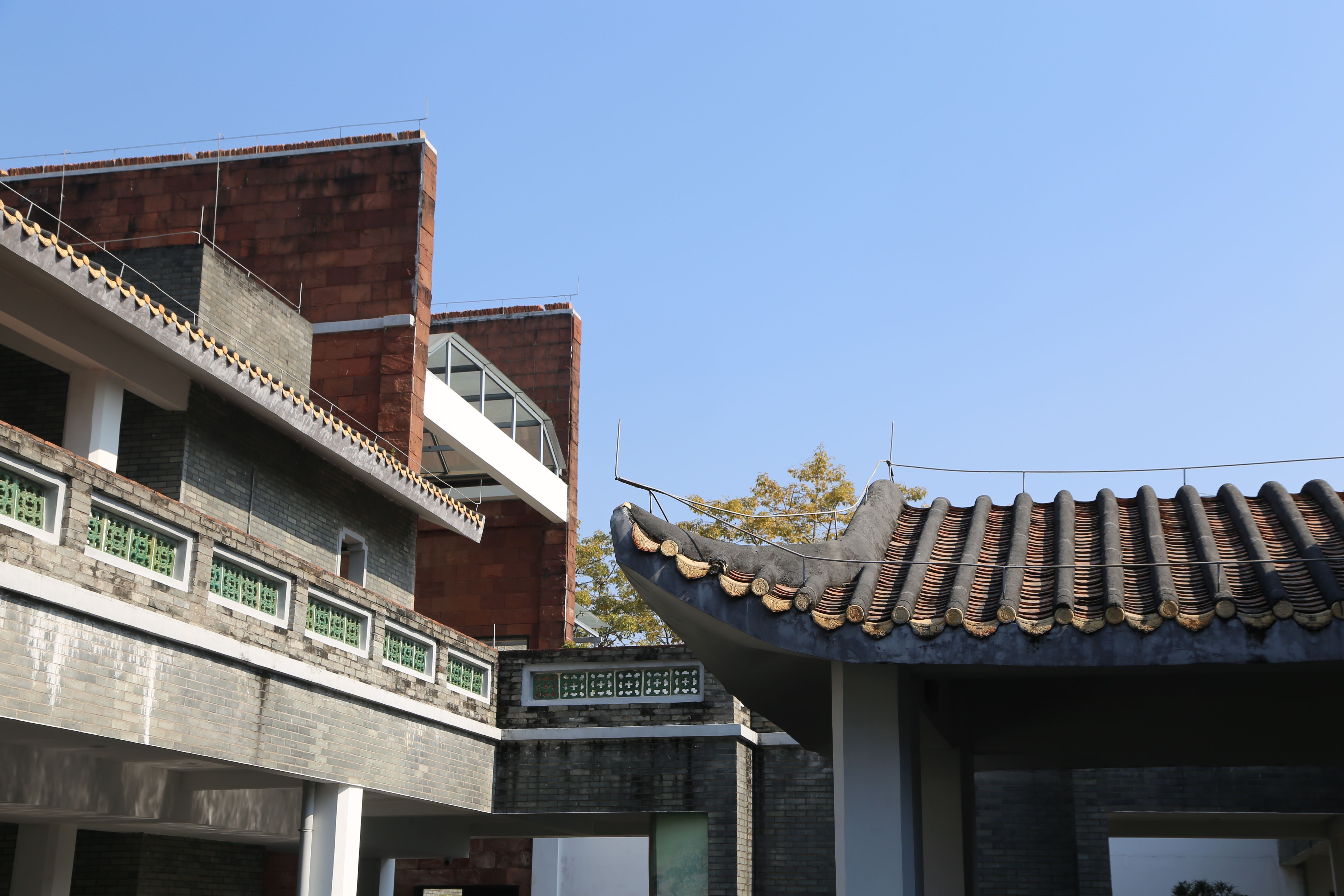 In the modern city, there is an old house with a tiled roof and a wall on one side of it