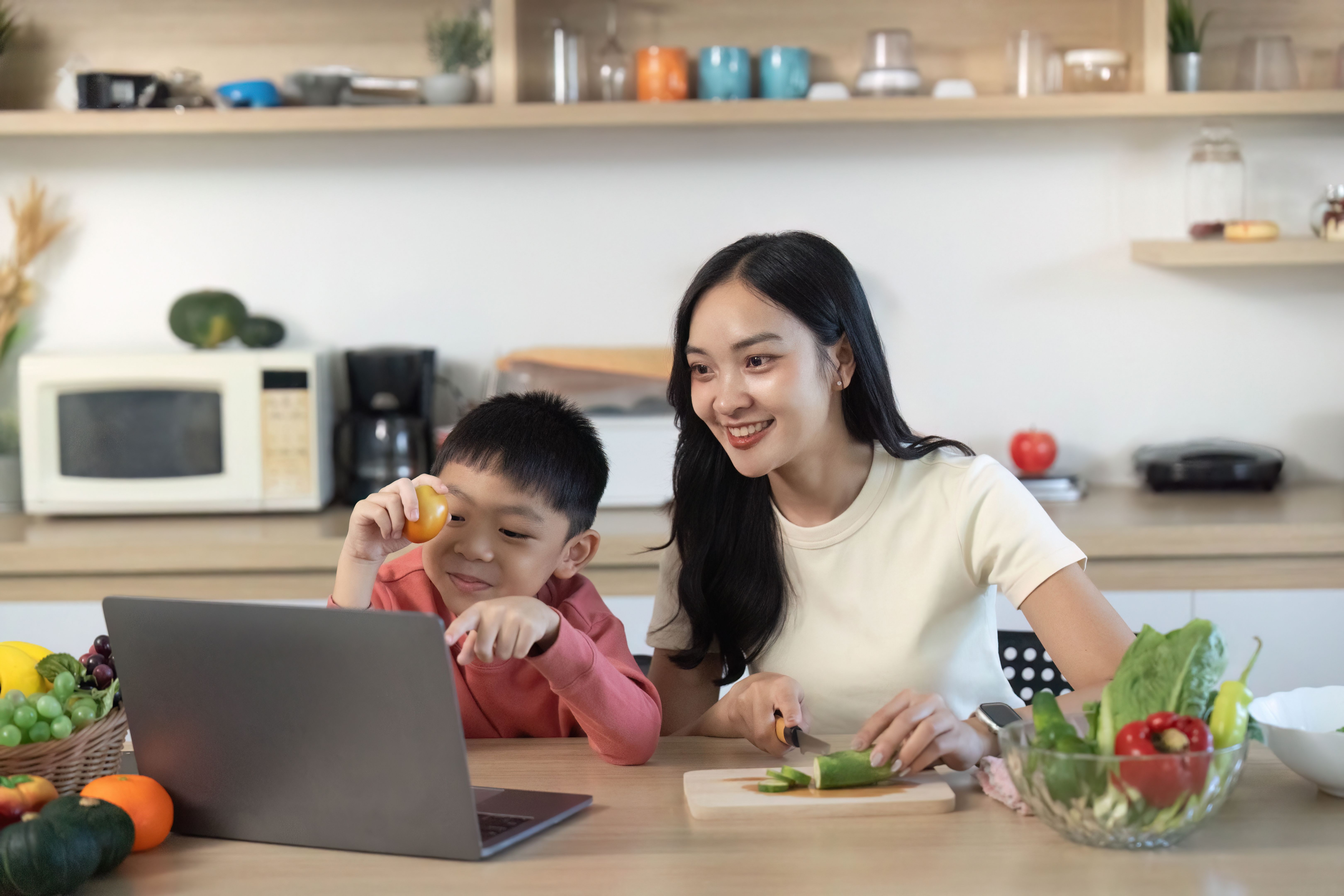 Cooking Together. Mother and son preparing healthy meal while watching online recipe.