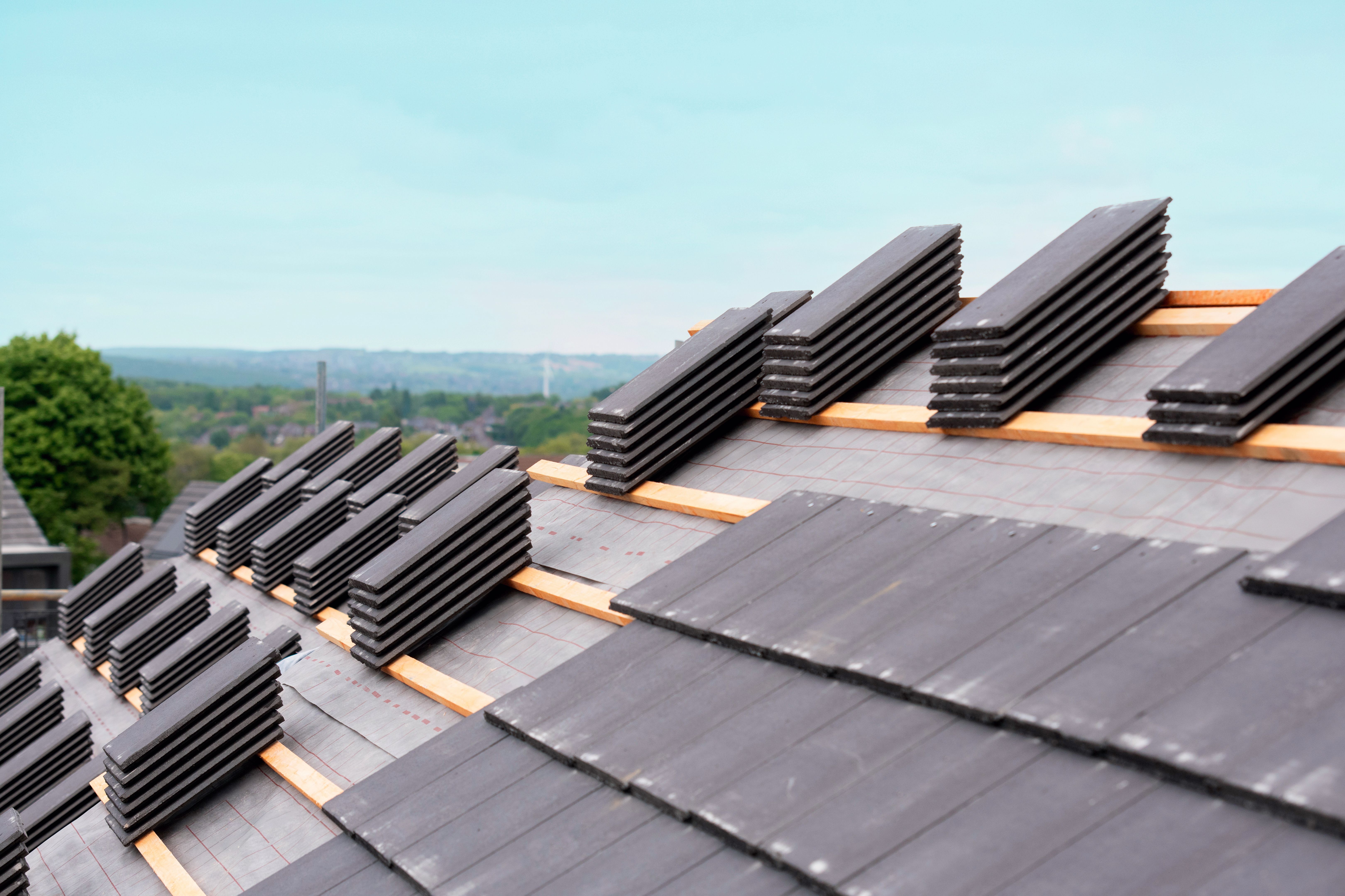 Roof tiles stacked and ready for installation on a residential building during overcast weather conditions