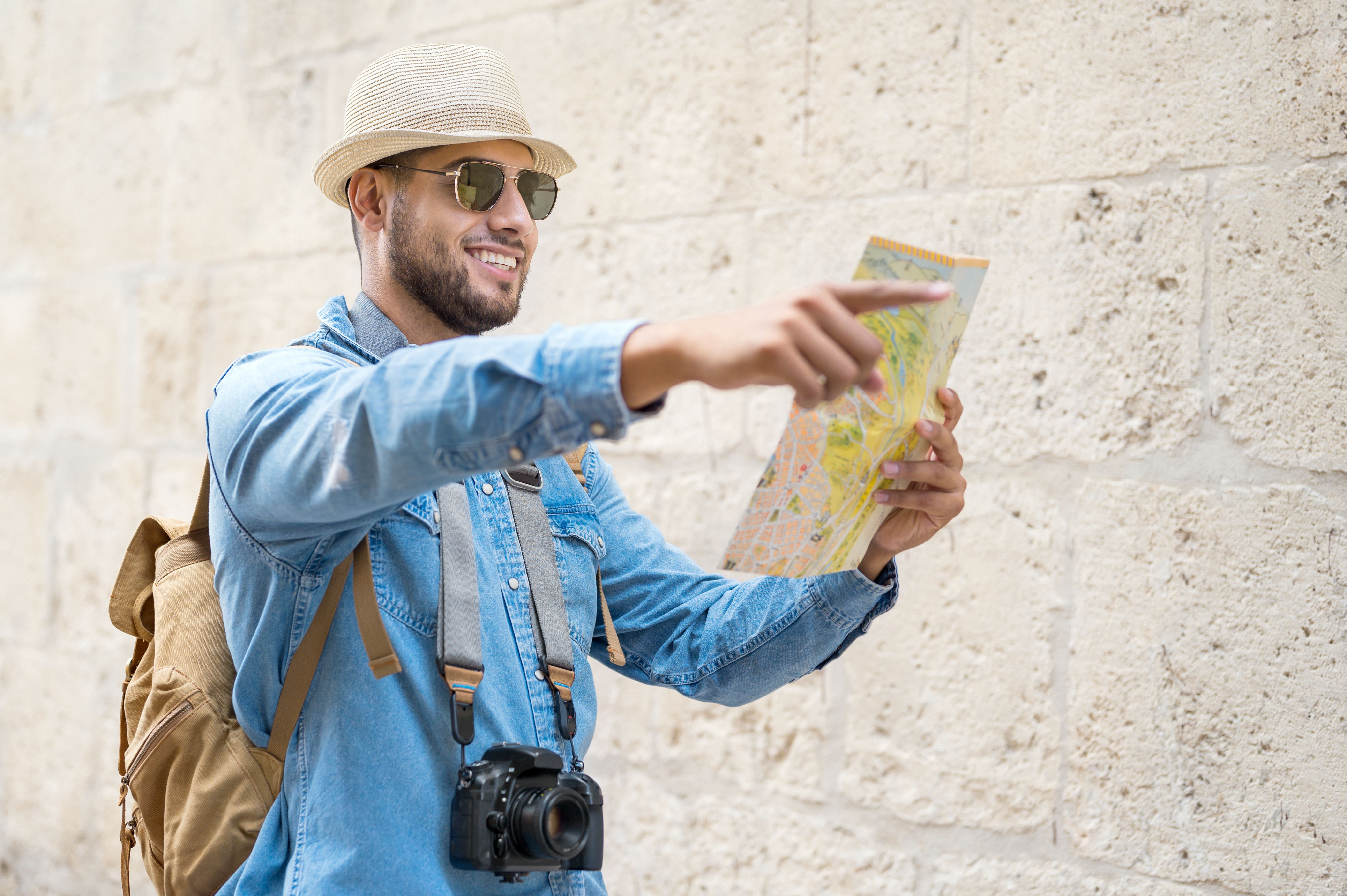 Handsome tourist man look at map while pointing finger in the direction of destination. Travel concept. Trip, backpacker tourist. High quality photo Handsome tourist man look at map while pointing finger in the direction of destination. Travel concept. Trip, backpacker tourist. High quality photo