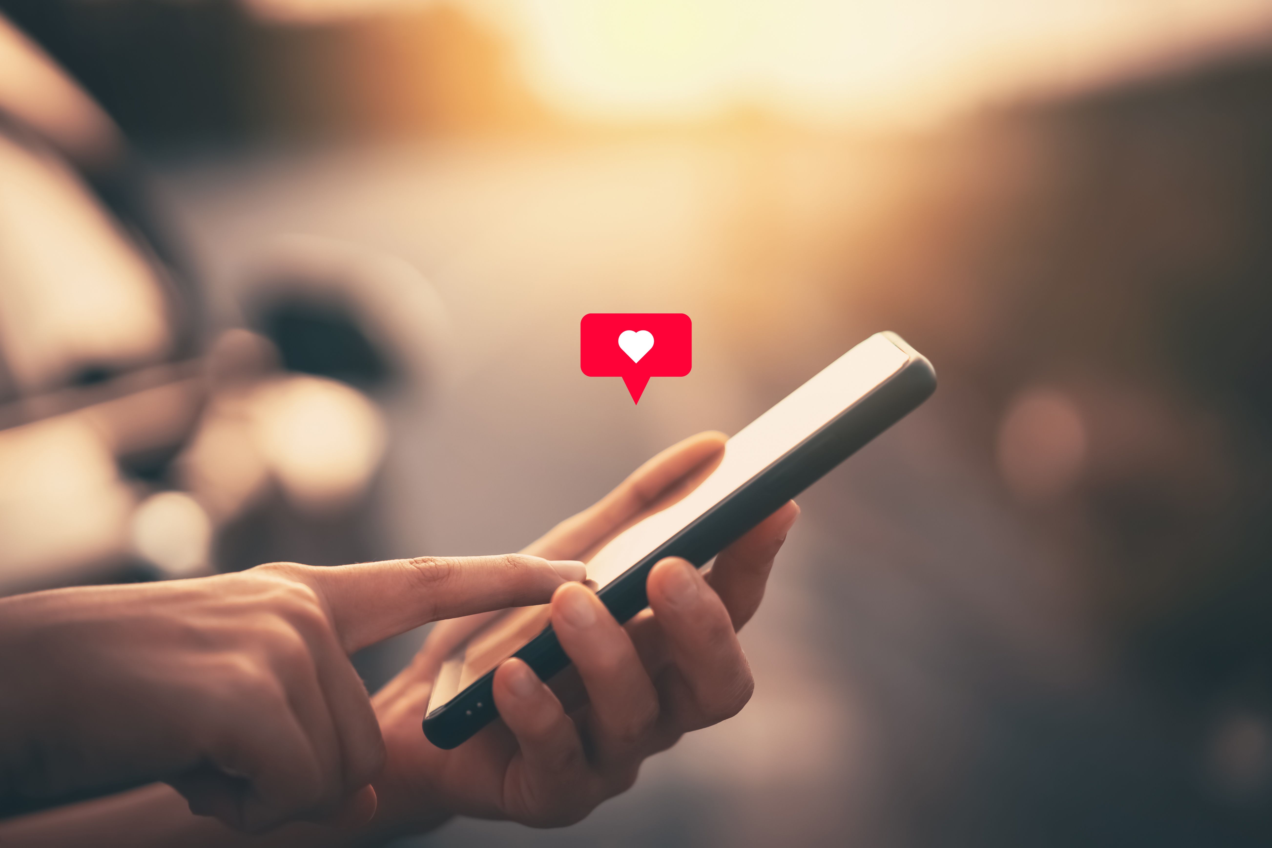 Cierre la mano de la mujer usando un teléfono inteligente con el icono del corazón en el fondo de la calle del parque al aire libre. Copia espacio de tecnología de negocios y concepto de vacaciones de viaje. Cierre la mano de la mujer usando un teléfono inteligente con el icono del corazón en el fondo de la calle del parque al aire libre. Copia espacio de tecnología de negocios y concepto de vacaciones de viaje.