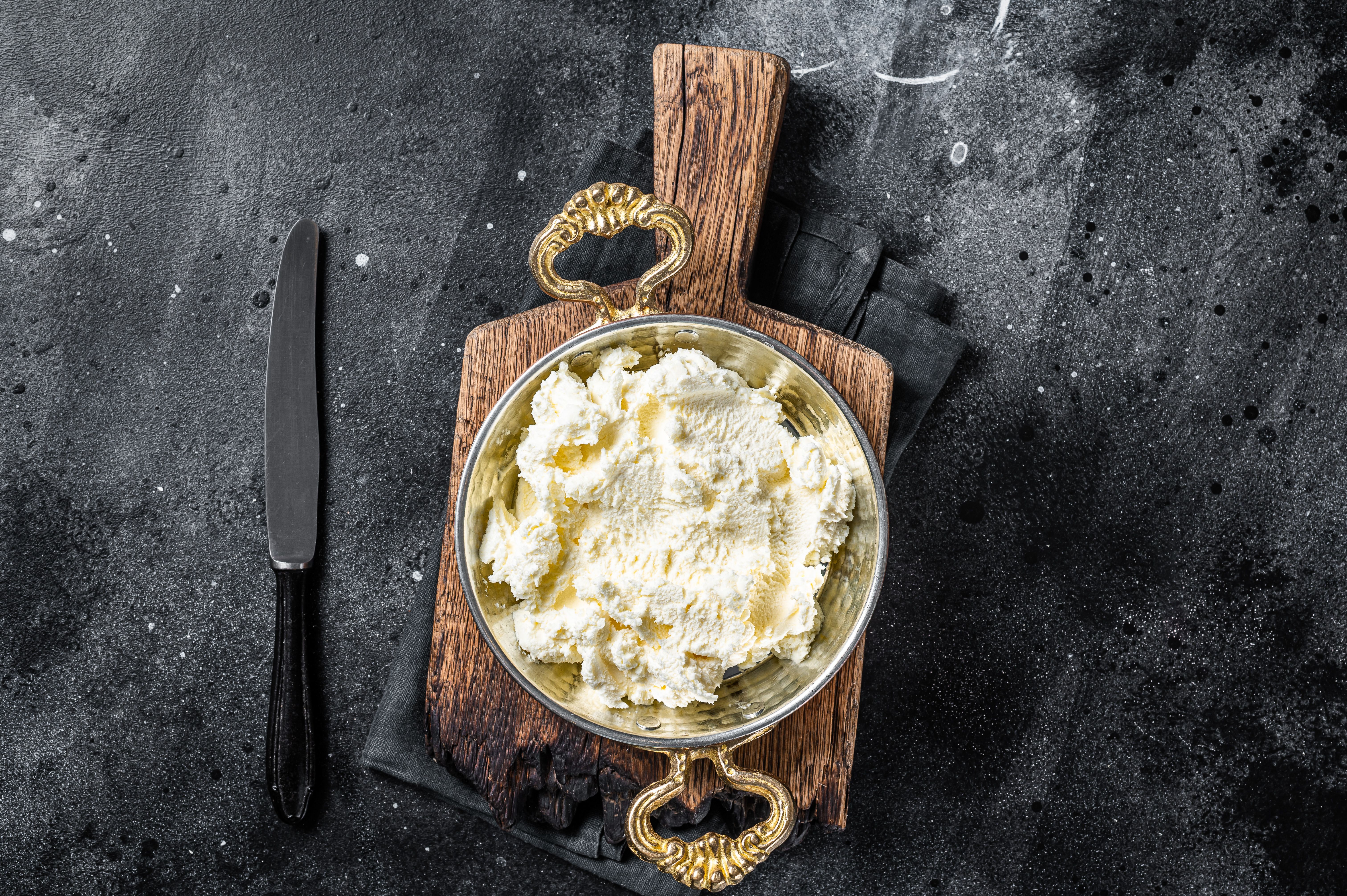 Kaymak Clotted cream, butter cream in a rustic pan. Black background. Top view