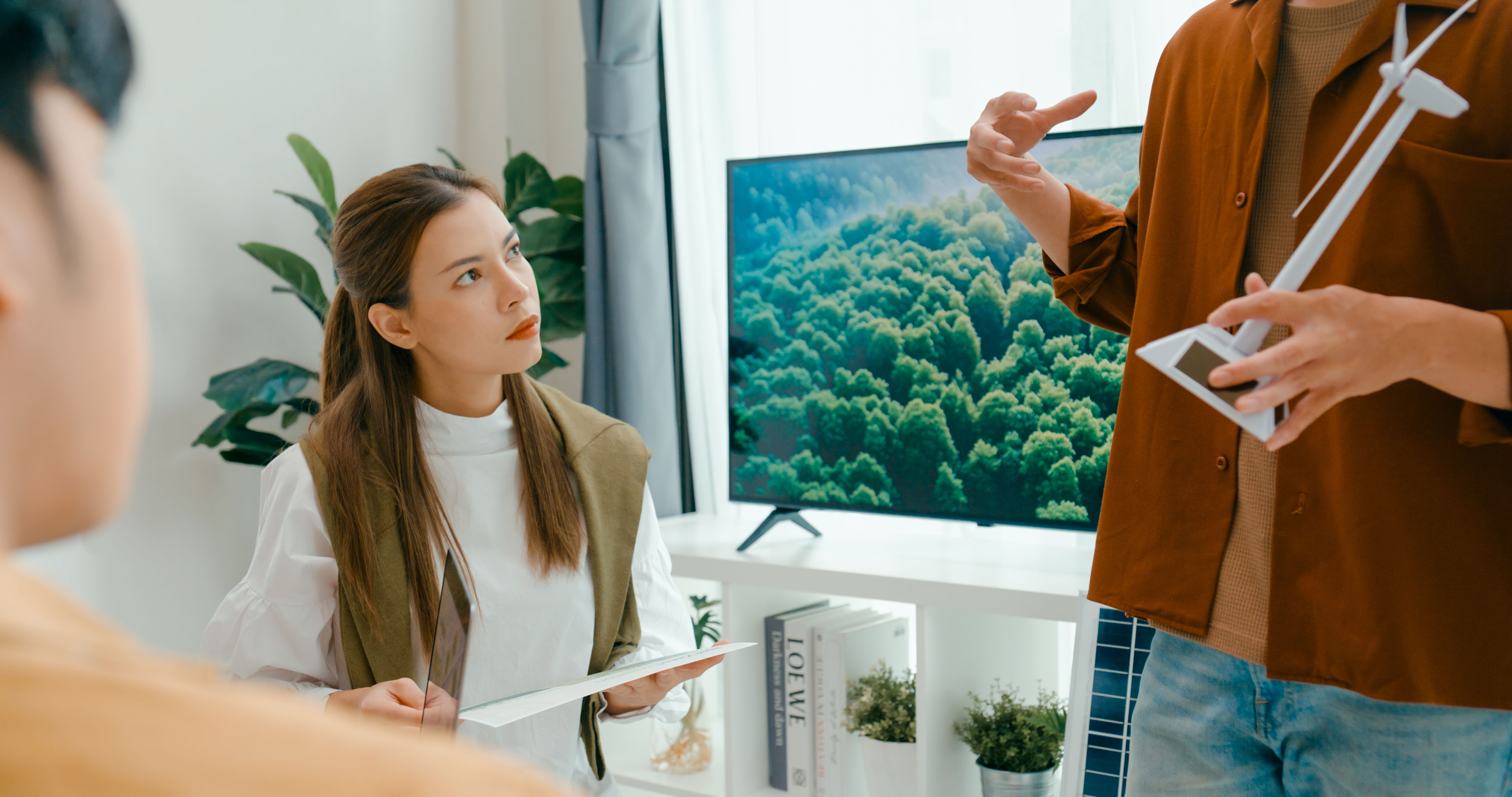 Closeup of team meeting focus on environmental strategy, using models of wind turbines and solar panels to discuss renewable energy solutions. Eco-Friendly Business Team Discussing ESG Goals.