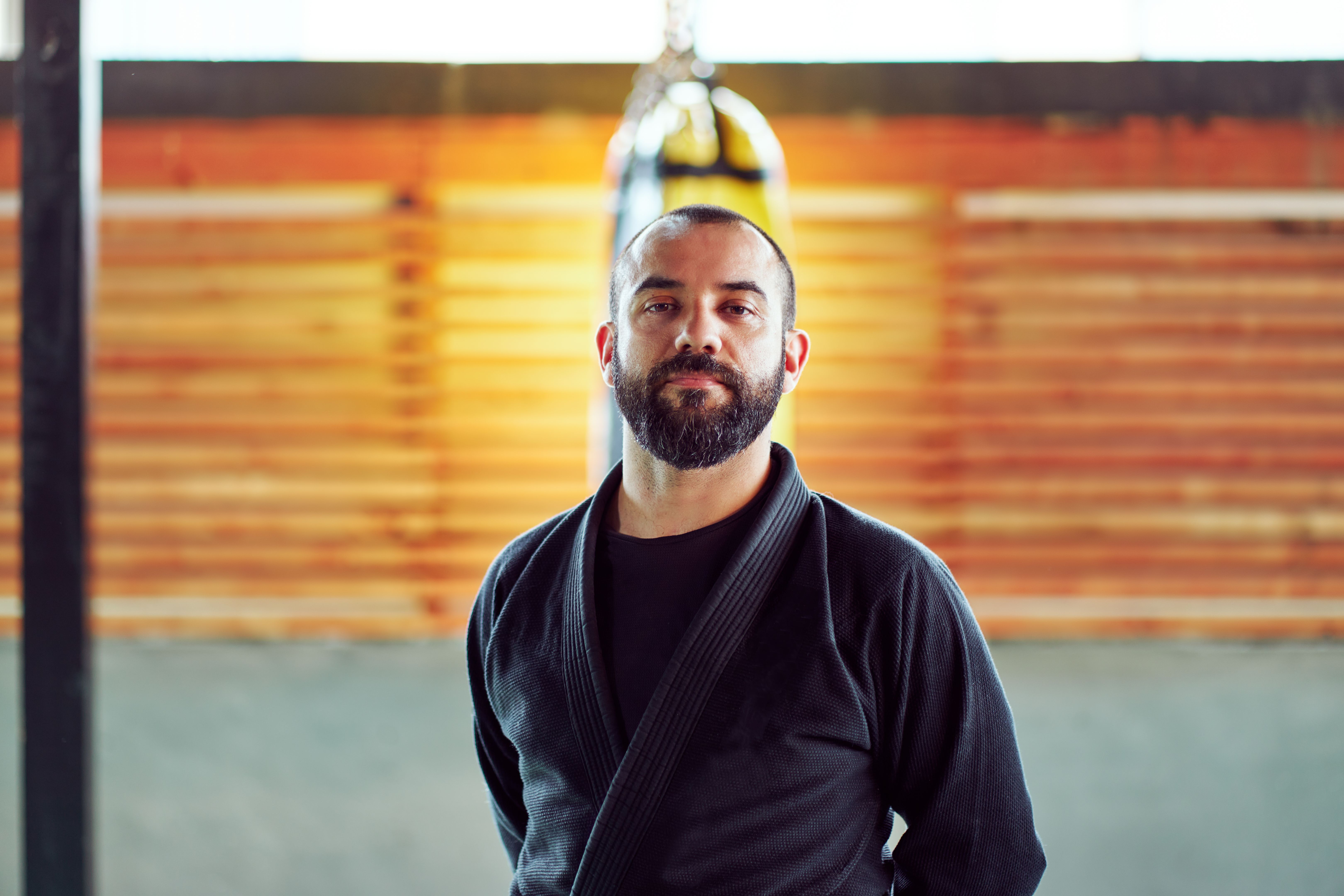 Portrait of a martial arts master posing in his dojo, wearing a black kimono and brown belt
