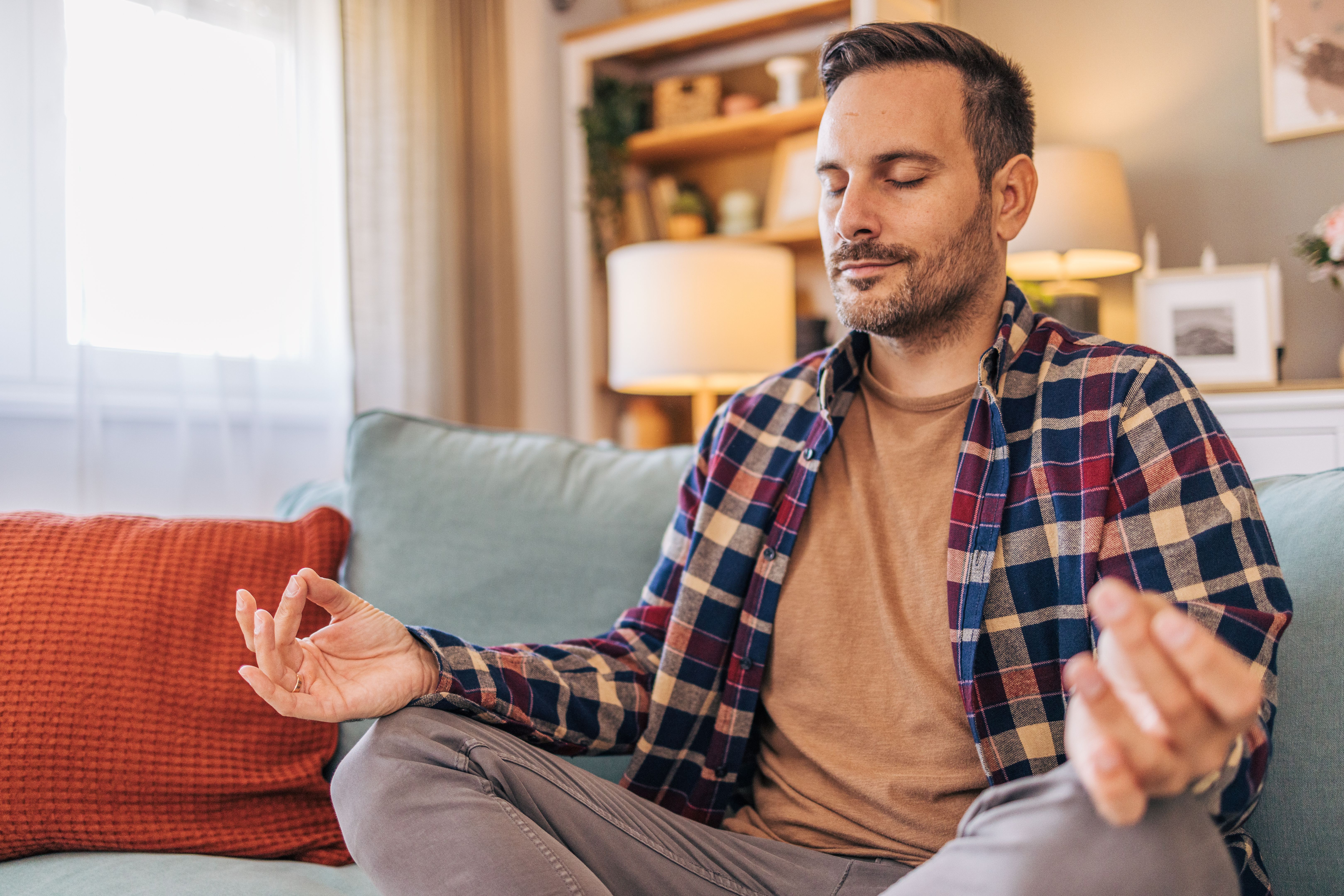 A mid-adult, cheerful, handsome man sitting on the floor in the living room, practicing yoga. A mid-adult, cheerful, handsome man sitting on the floor in the living room, practicing yoga.