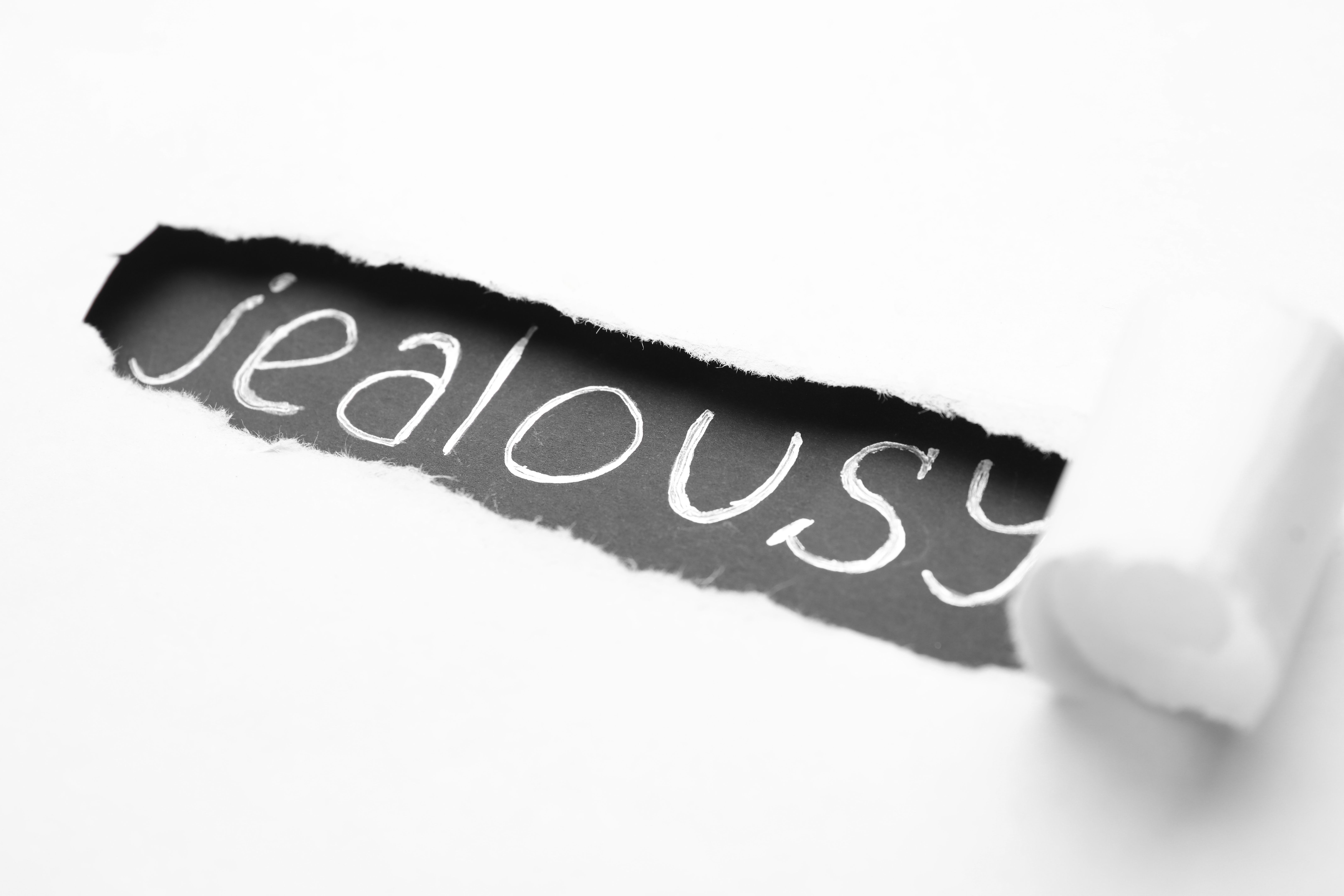 Word JEALOUSY under ripped paper as background Word JEALOUSY under ripped paper as background