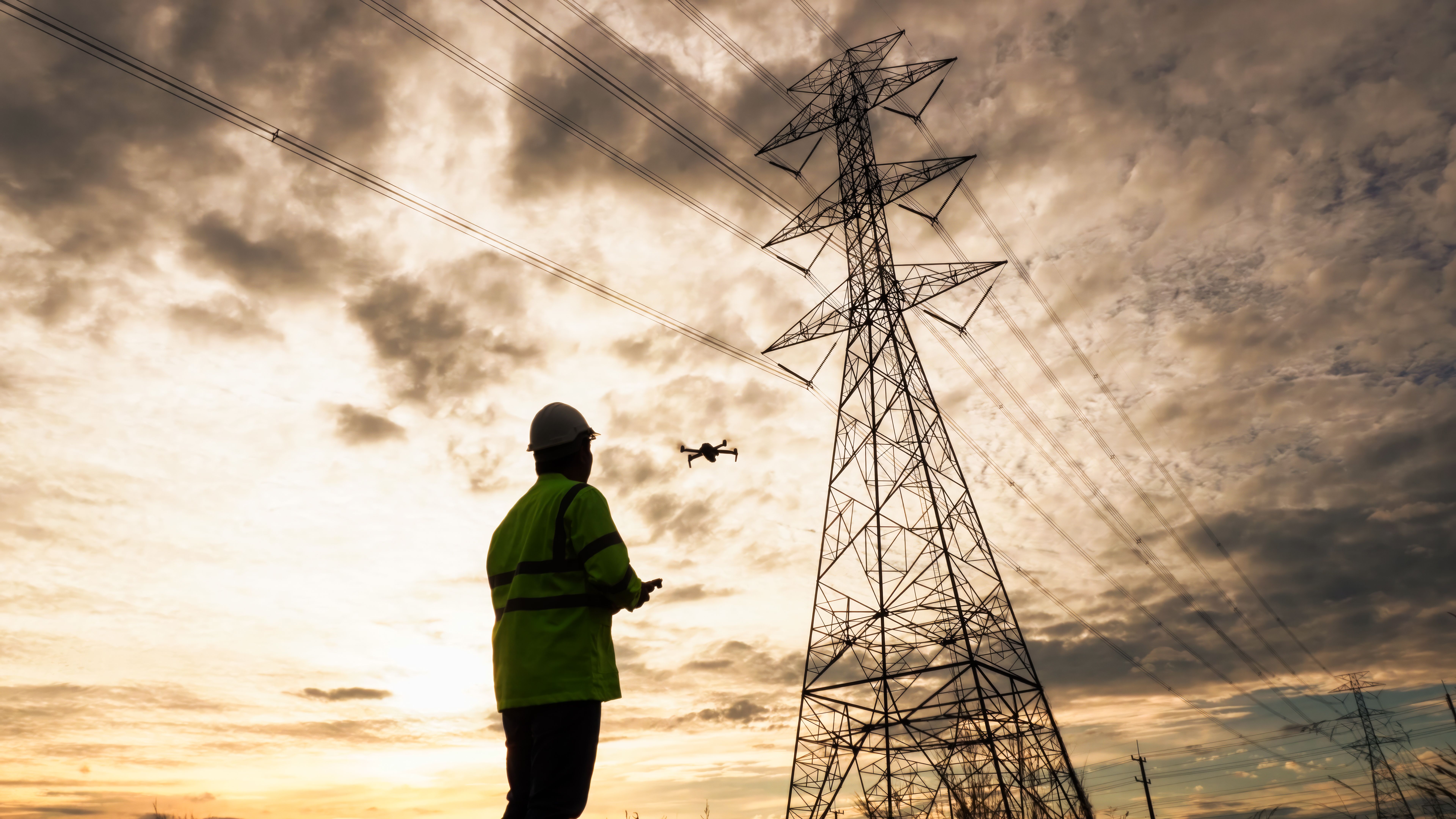 Silhouette of engineer man using drone checking high-voltage power lines. Silhouette of engineer man using drone checking high-voltage power lines.