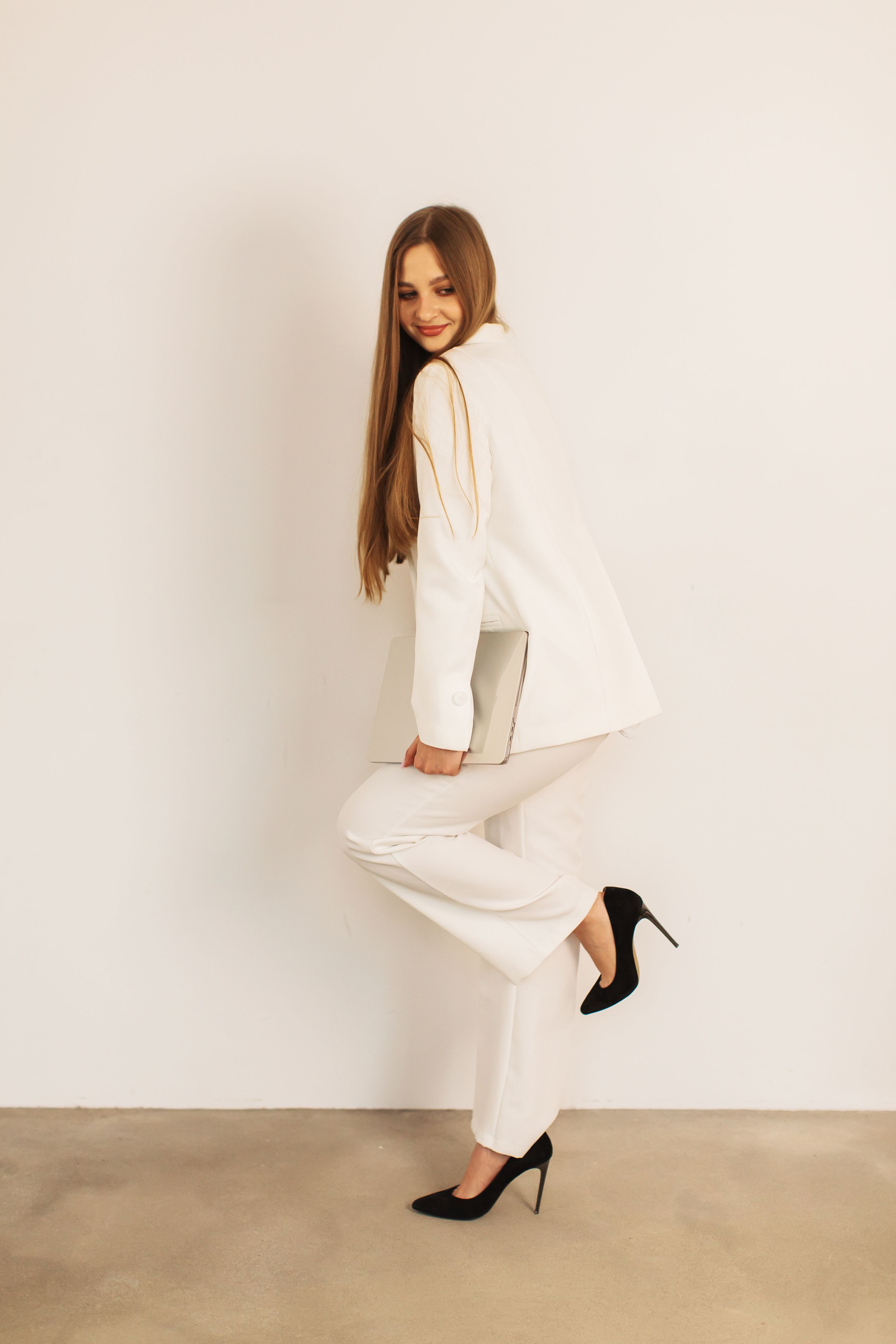 Blonde woman in white business suit working at a laptop. Style. Long hair