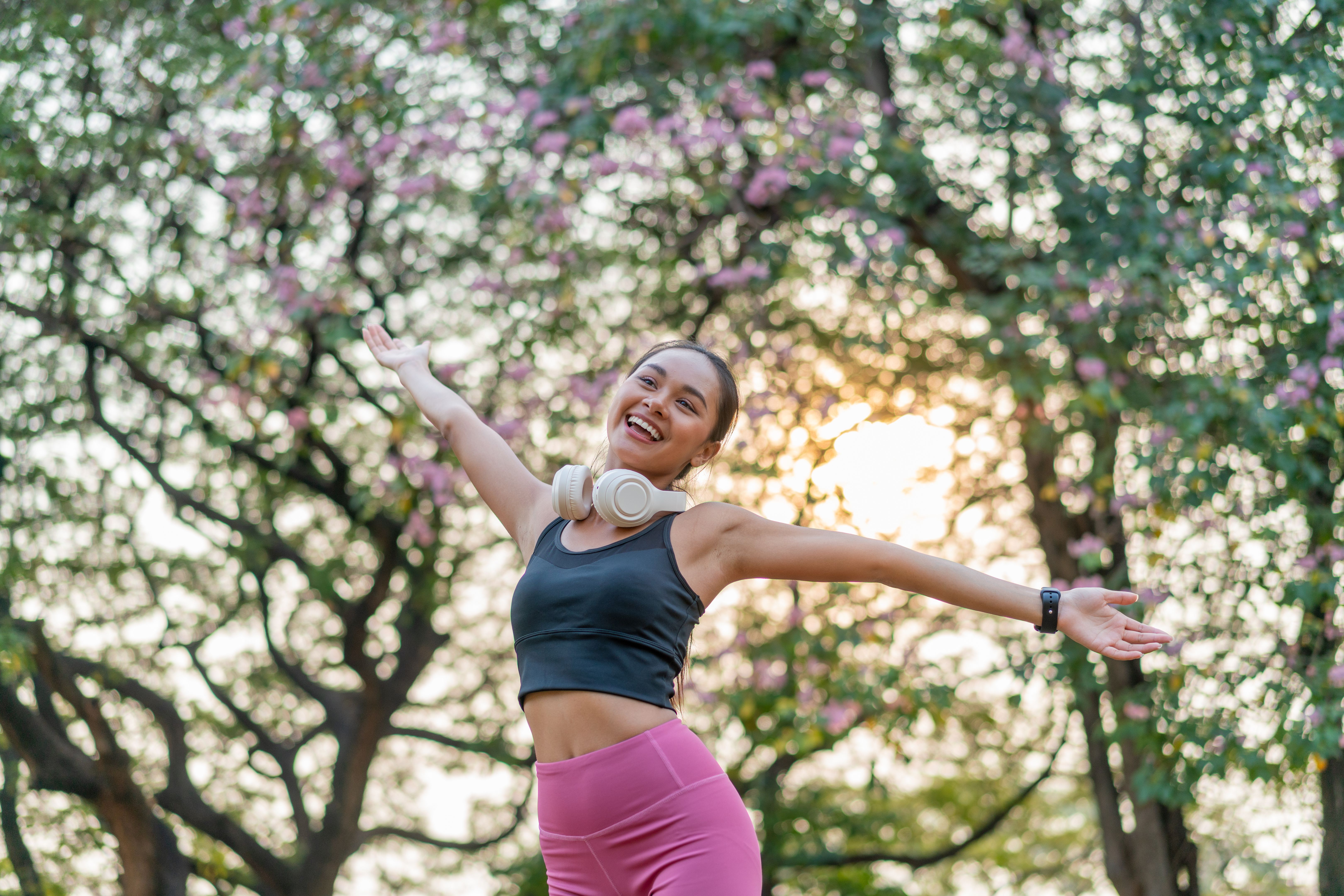 Asian Woman with Headphones Enjoying Music While Exercise in Nature at Sunset Asian Woman with Headphones Enjoying Music While Exercise in Nature at Sunset