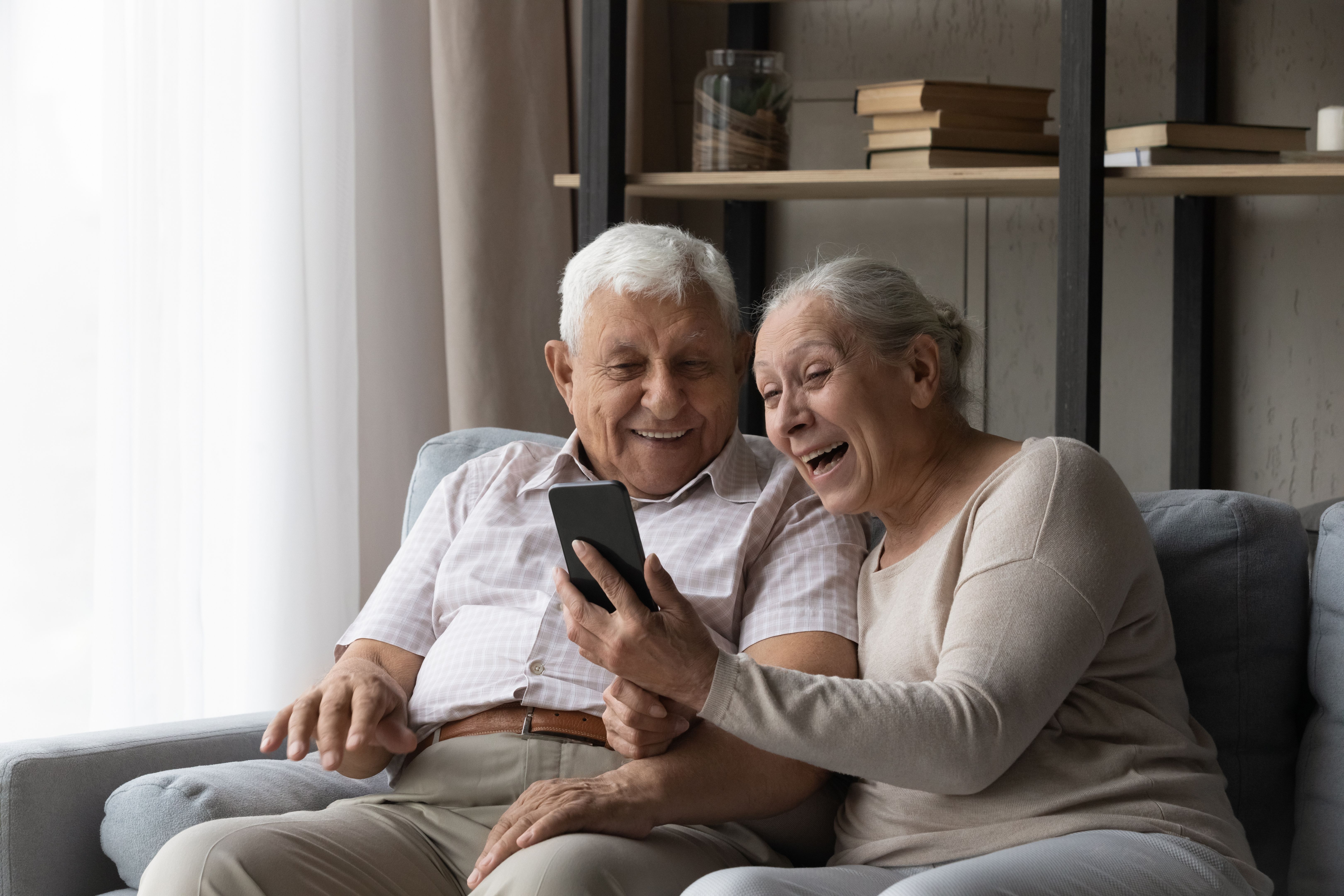 Heureux couple marié plus âgé excité utilisant un smartphone