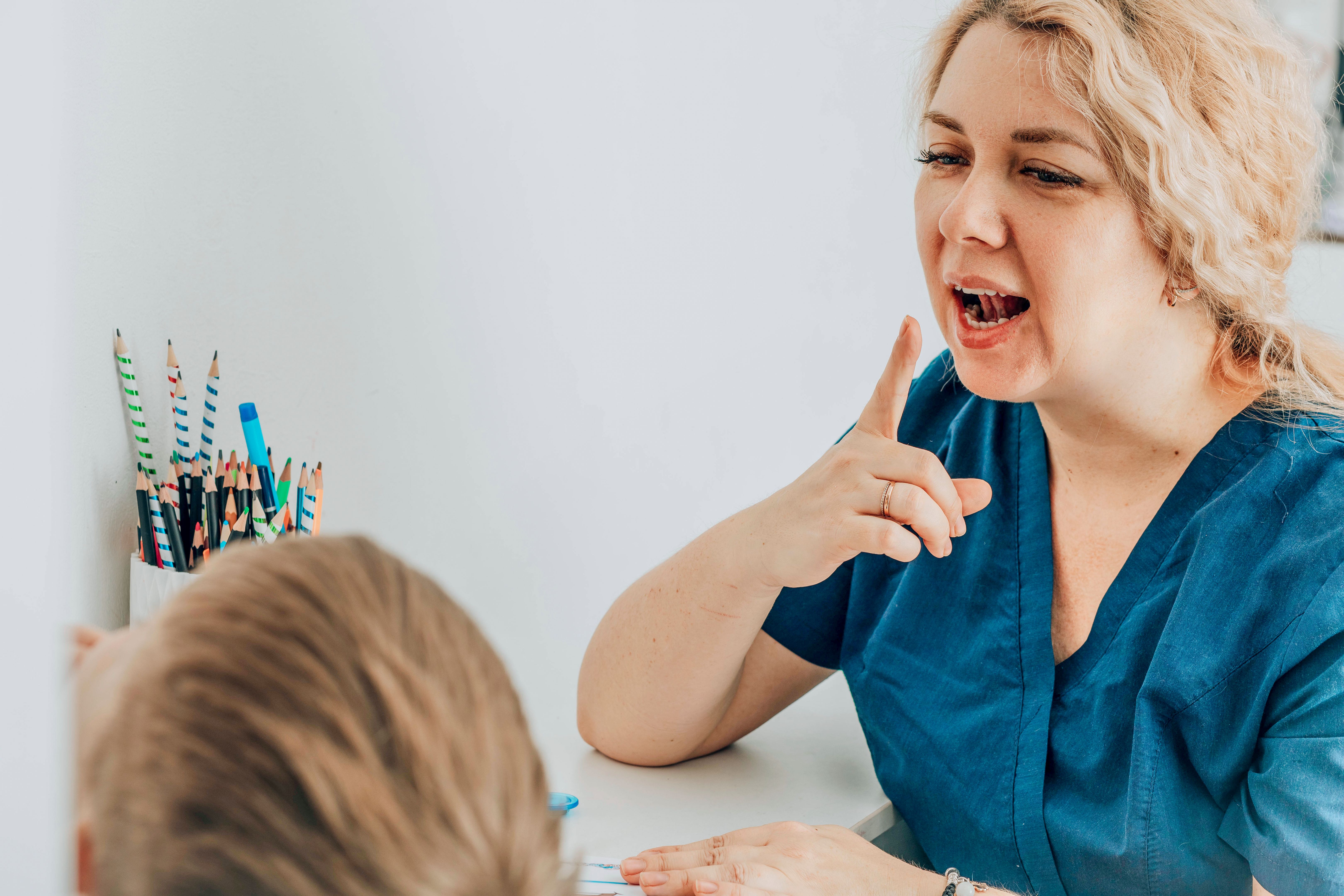 woman speech therapist teaching young boy in a classroom setting, engaging with a lively expression, concept of early childhood education, special education