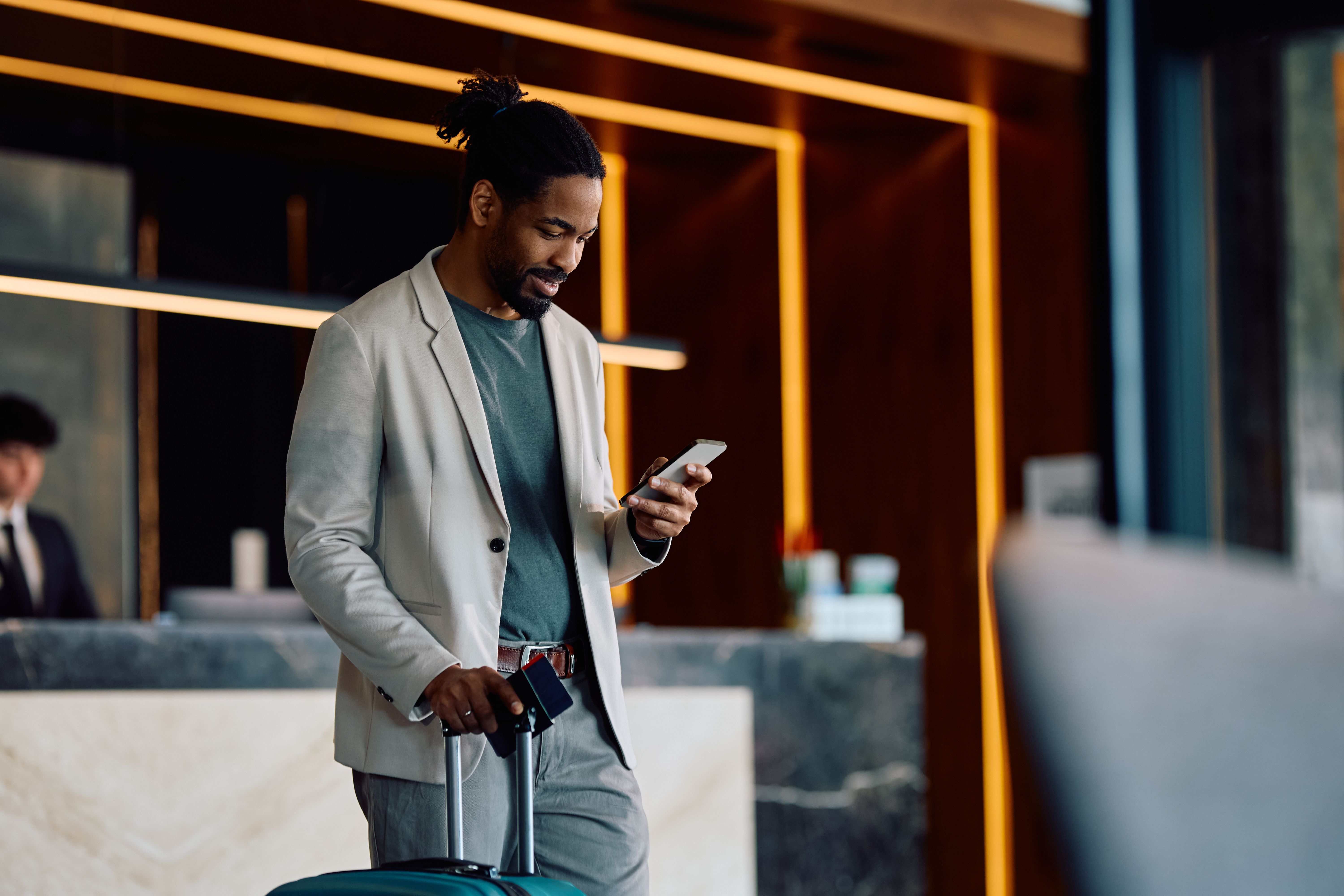 Happy black man using cell phone in a hotel lobby. Happy black man using cell phone in a hotel lobby.