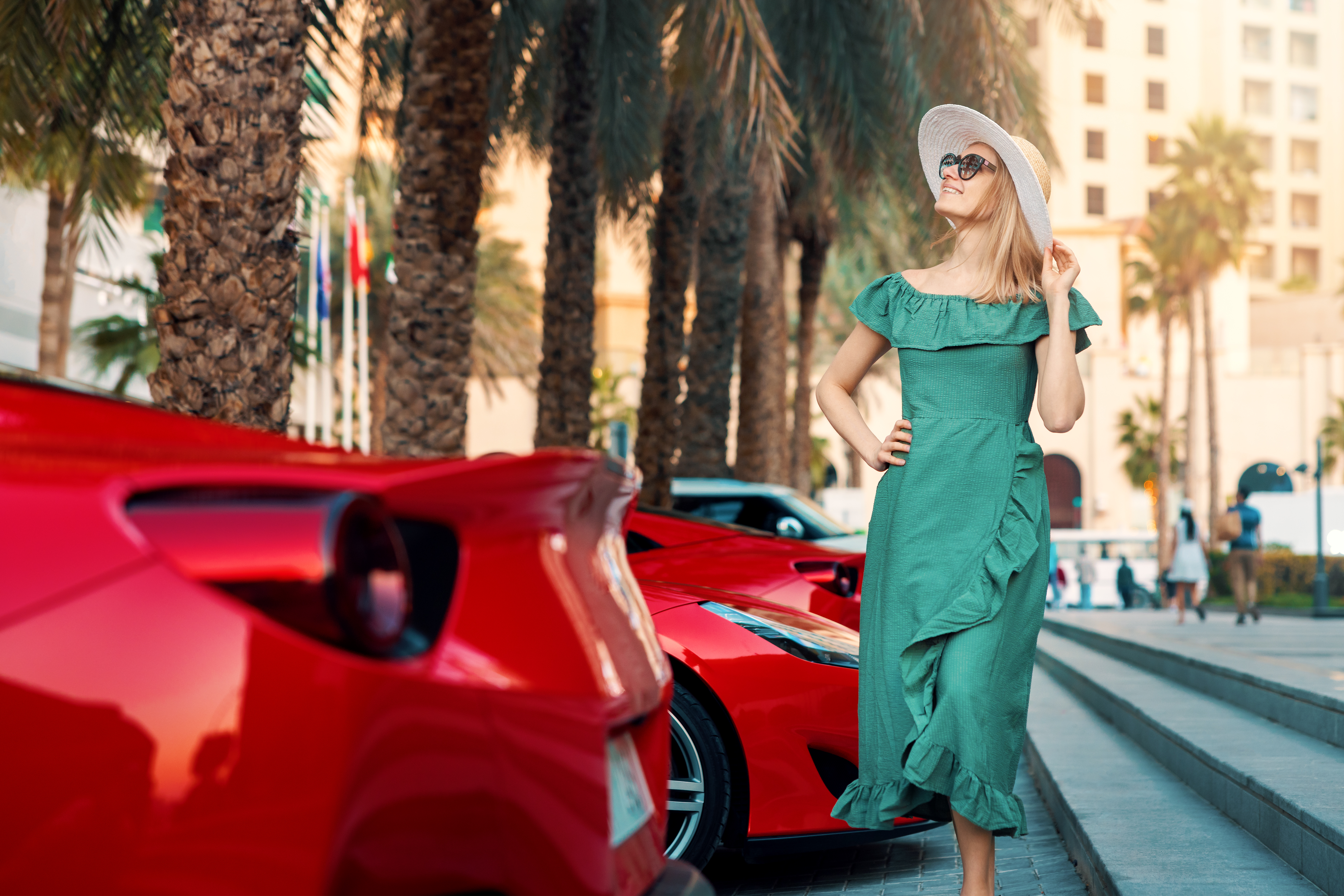 fashion woman in green dress walk Dubai city streets. stands next to luxury sport cars. Arab Emirates travel