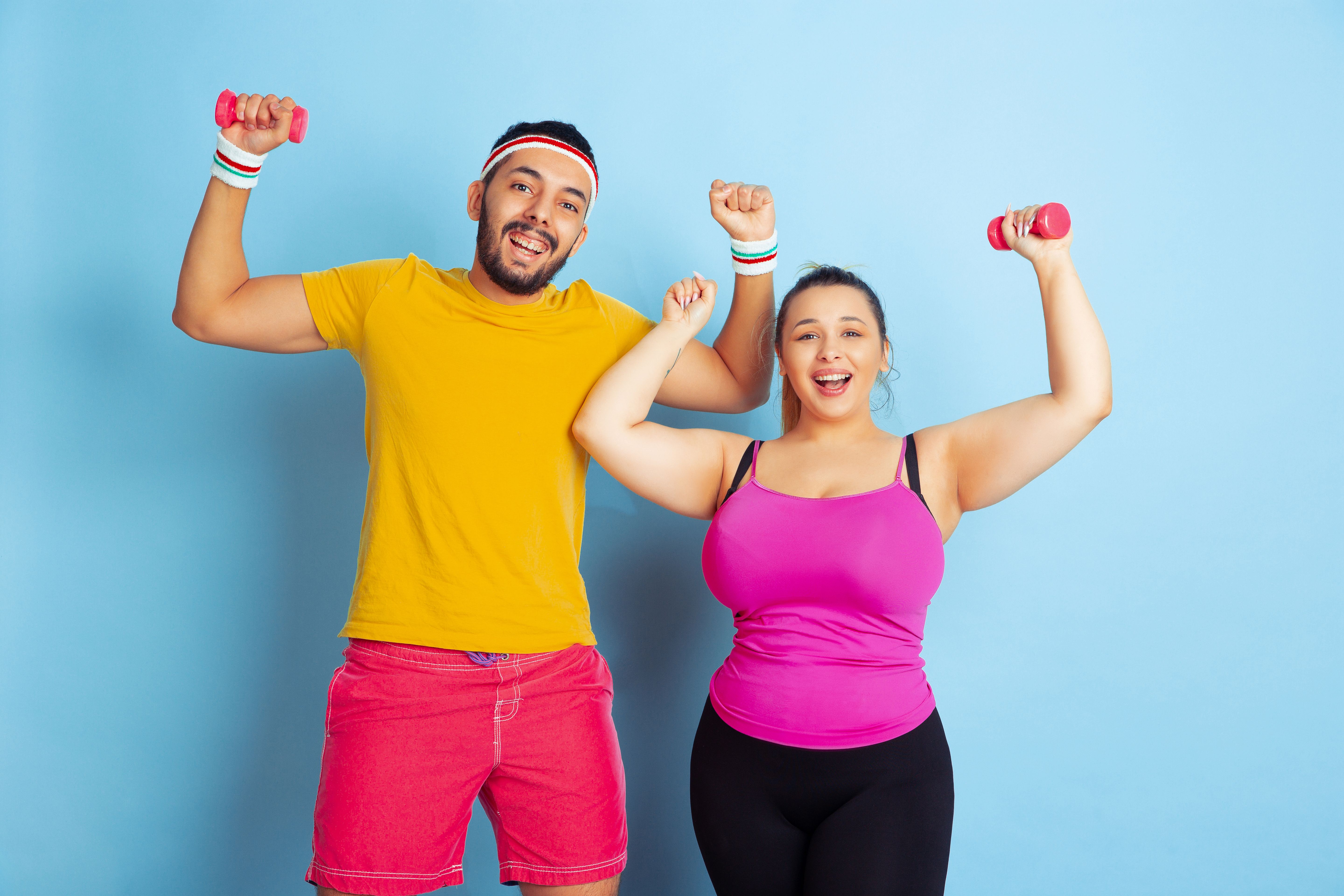 Young pretty caucasian couple in bright clothes training on blue background Young pretty caucasian couple in bright clothes training on blue background