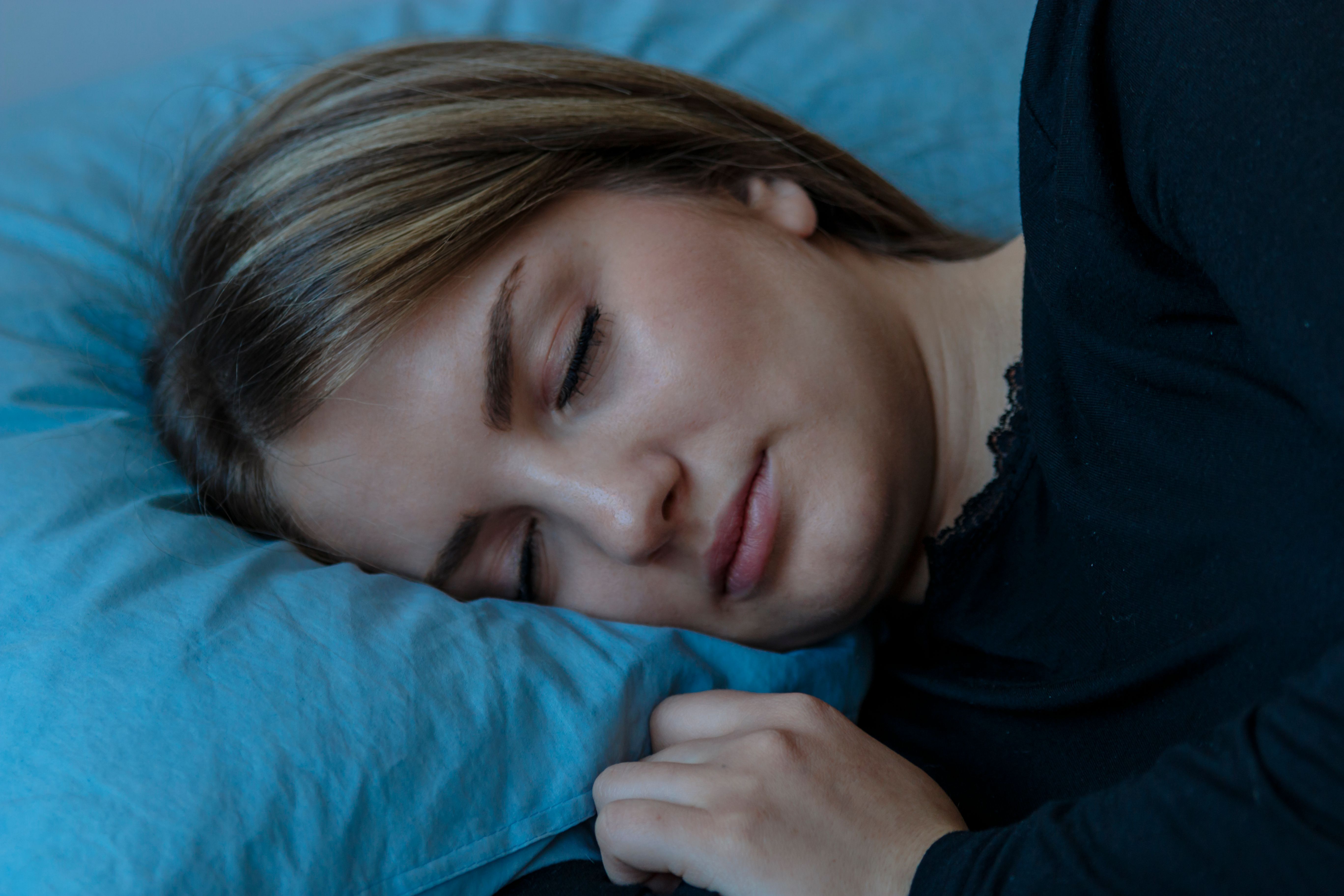 Beautiful young brunette woman sleeping in a white bed.