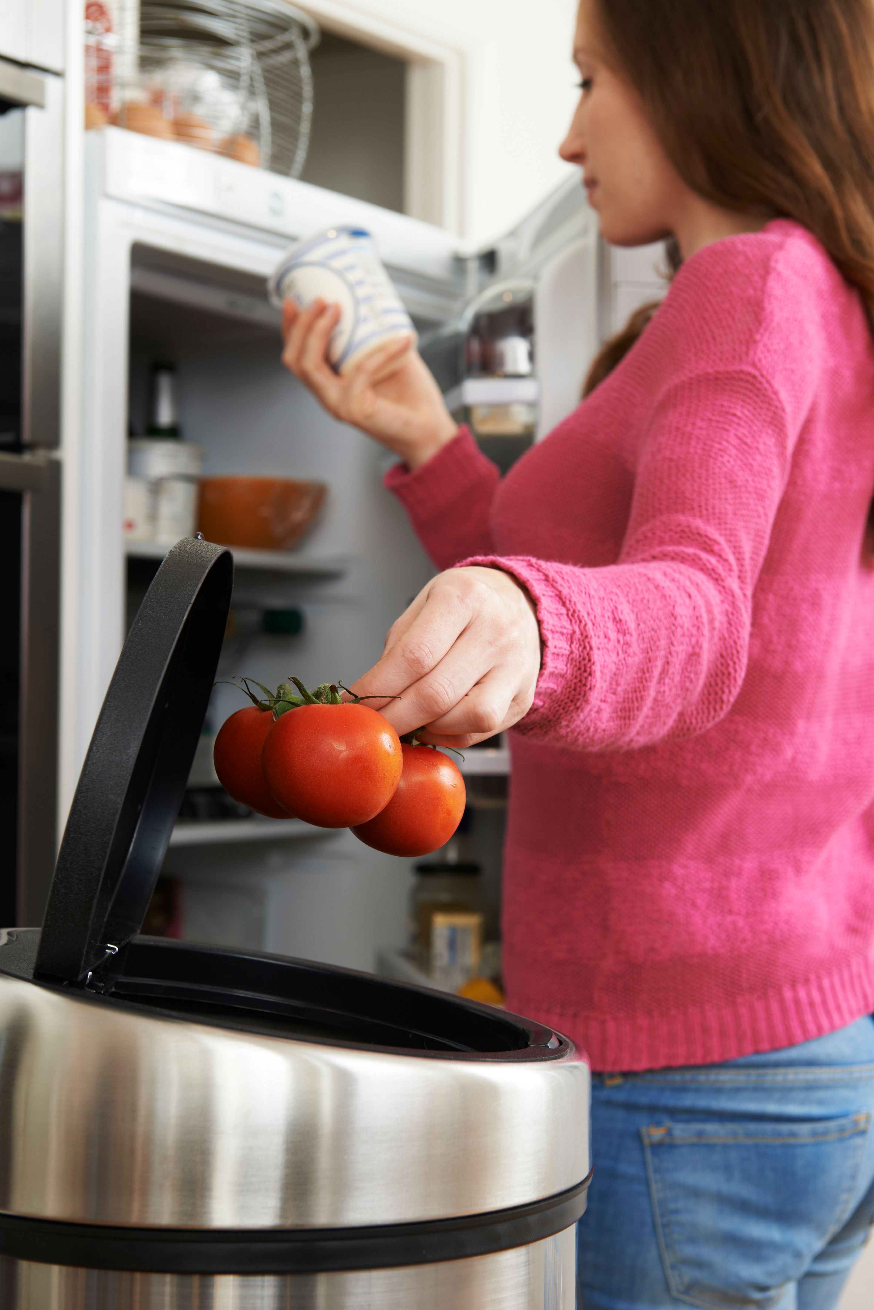 Woman Throwing Away Out Of Date Food In Refrigerator Woman Throwing Away Out Of Date Food In Refrigerator
