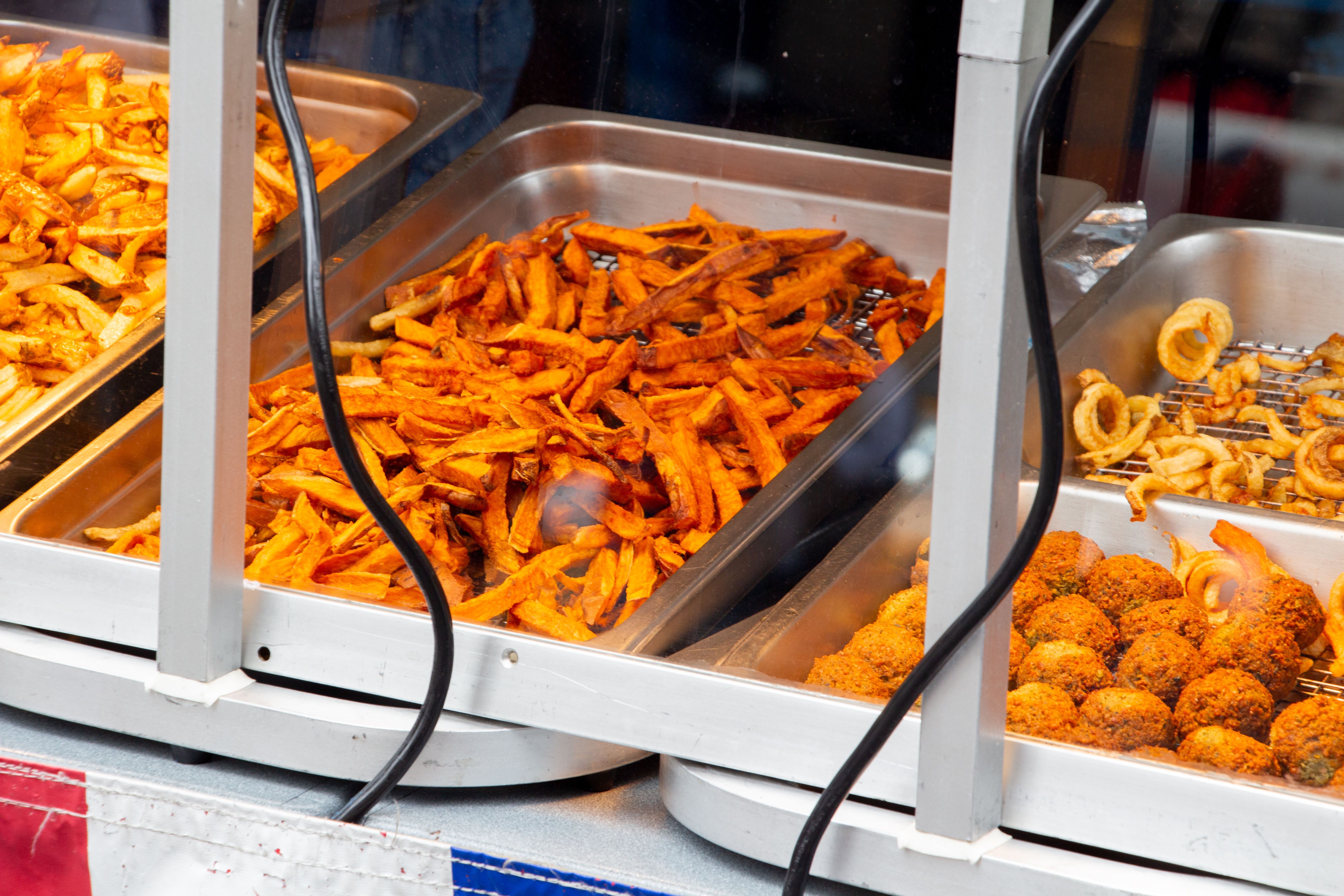 Sweet potato fries and other fried servings on display counter of an food truck Sweet potato fries and other fried servings on display counter of an food truck