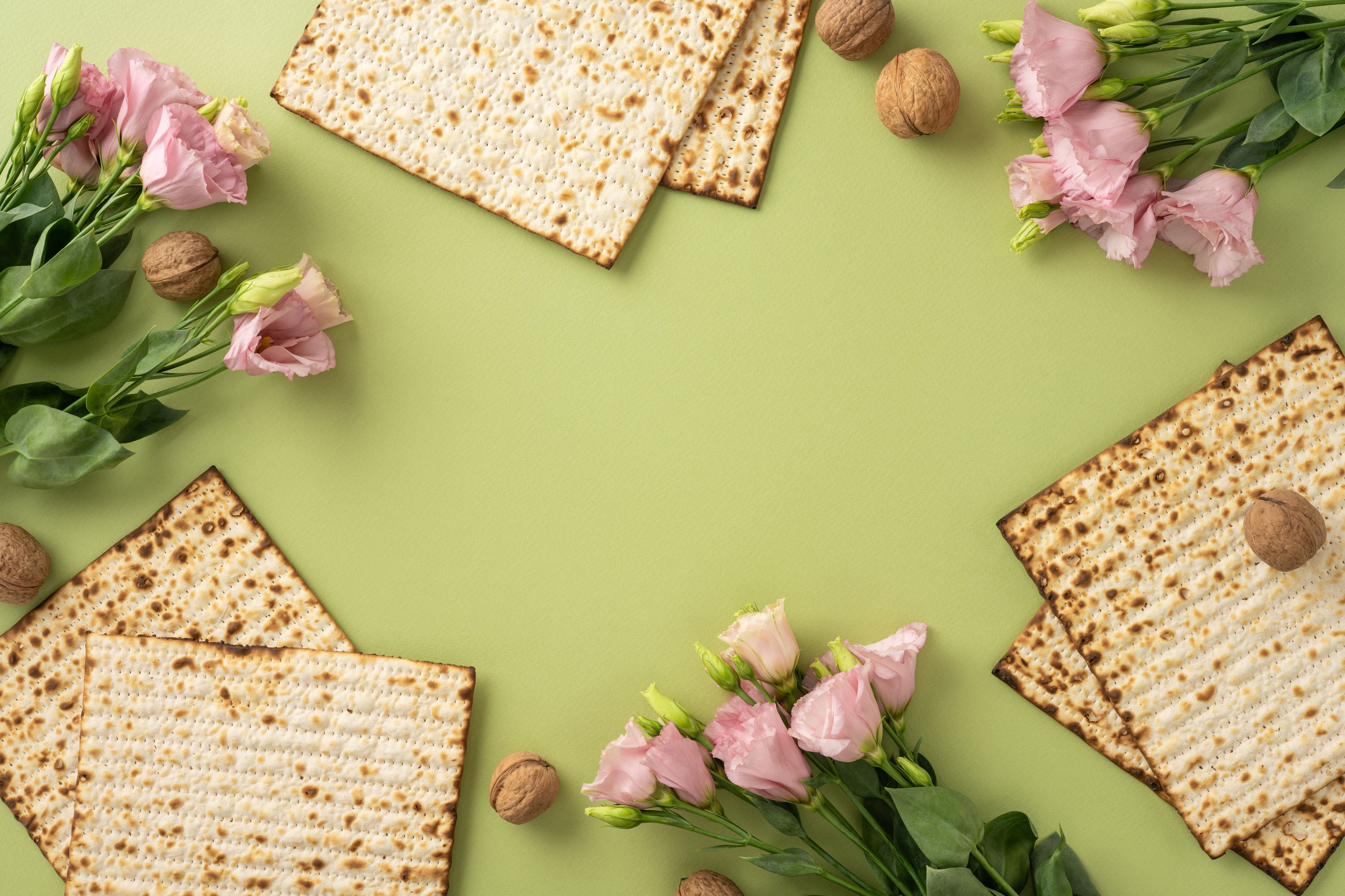 Pink flowers and traditional matzah crackers displayed on a green background, perfect for celebrating Passover and spring themes