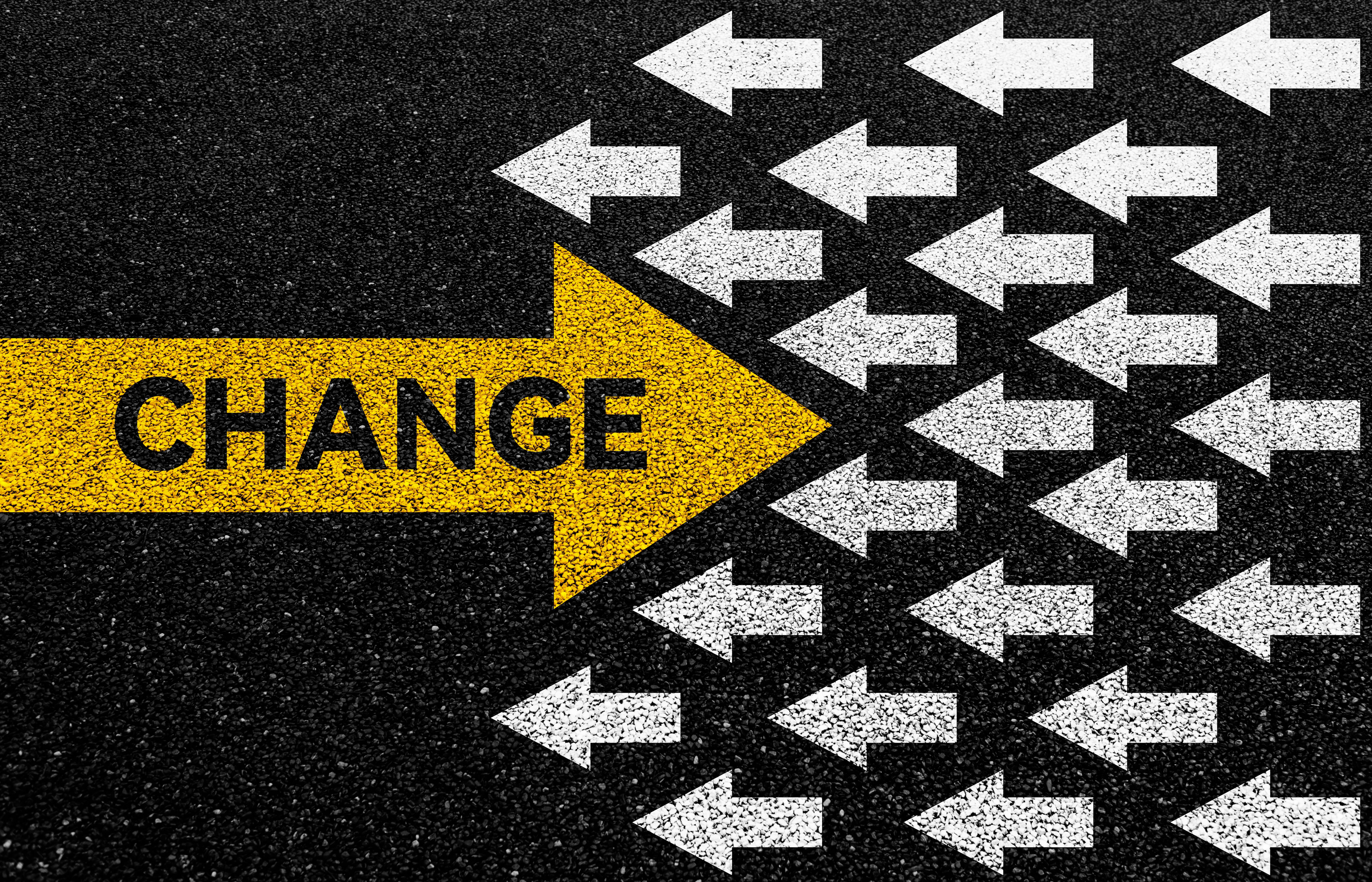 Big yellow arrow opposite direction with white arrows on asphalt road