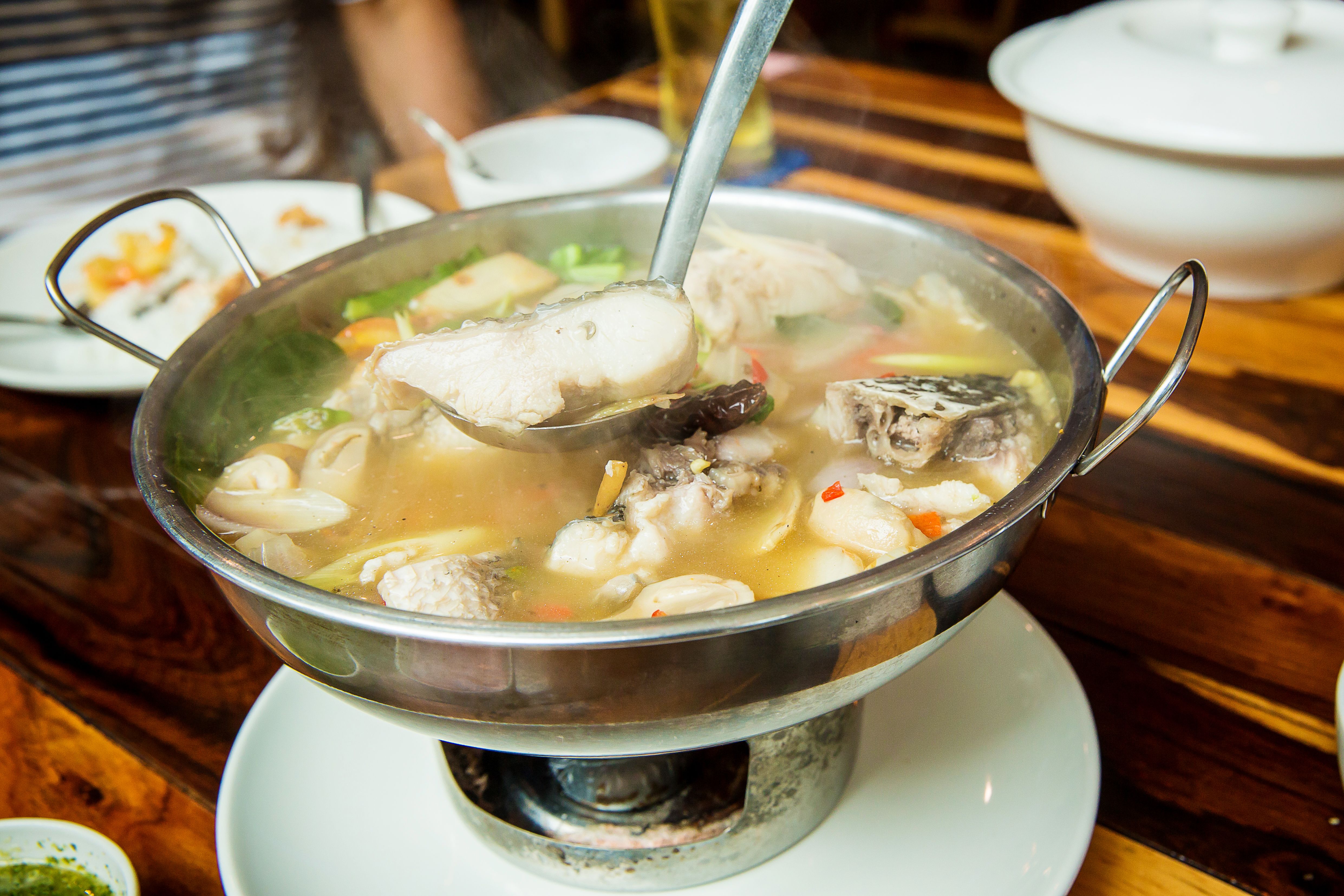 Thai spicy freshwater fish soup with herbs, served in big bowl. Tom Yam Pla. Thai famous street local food.