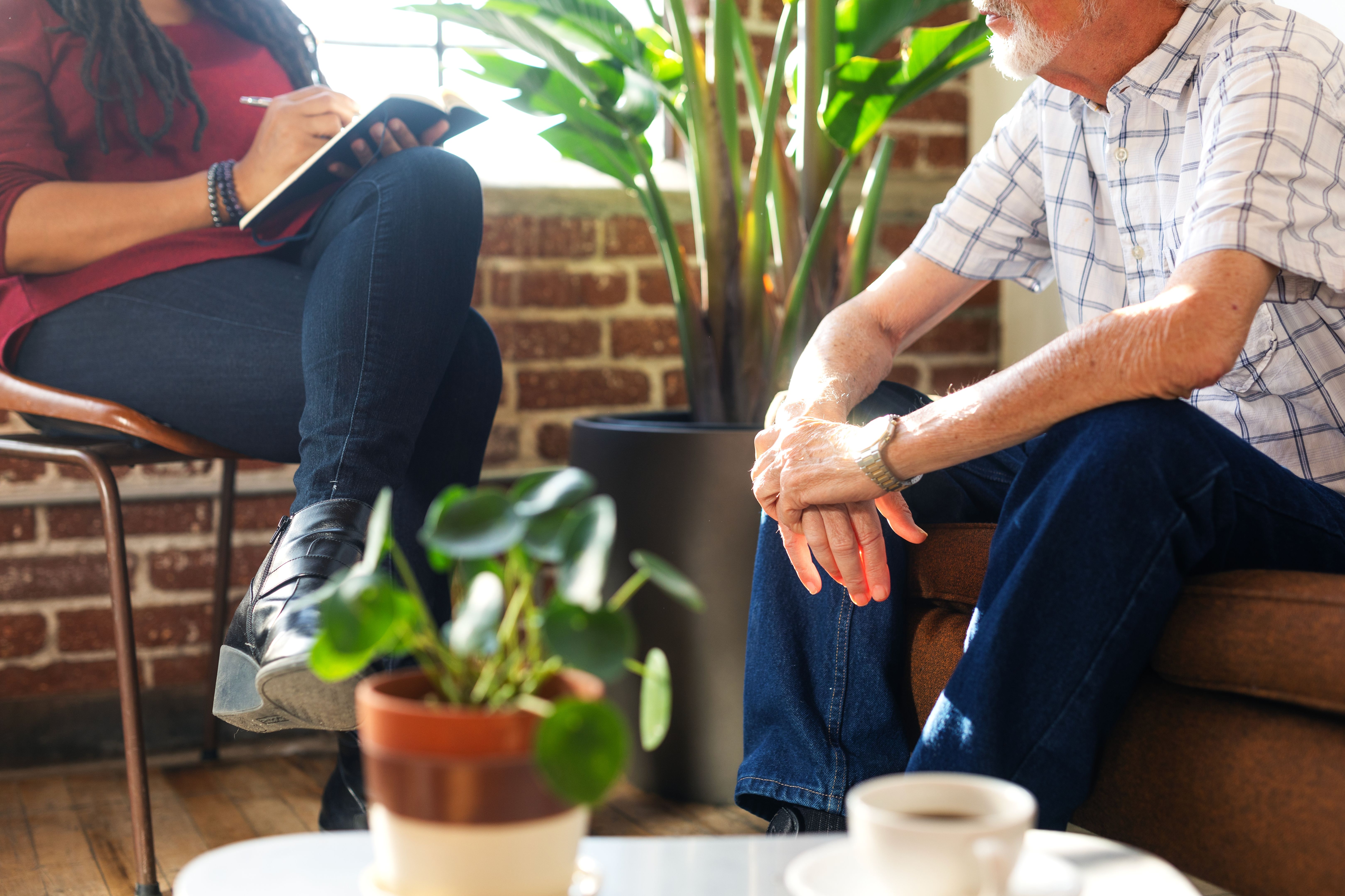 Therapy meeting with two people, one taking notes, the other listening.
