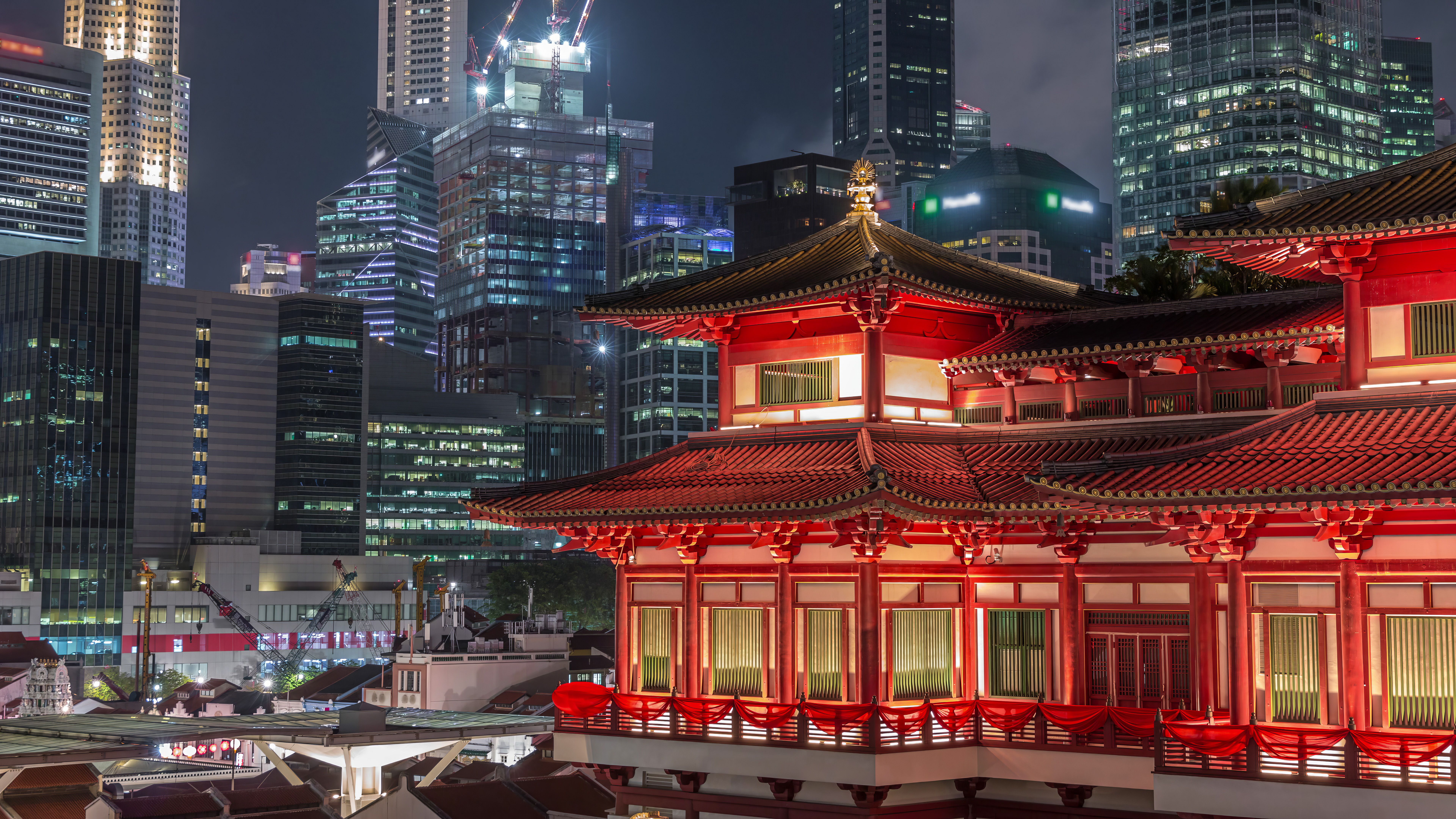 The Buddha Tooth Relic Temple comes alive at night timelapse in Singapore Chinatown, with the city skyline in the background. The Buddha Tooth Relic Temple comes alive at night timelapse in Singapore Chinatown, with the city skyline in the background.