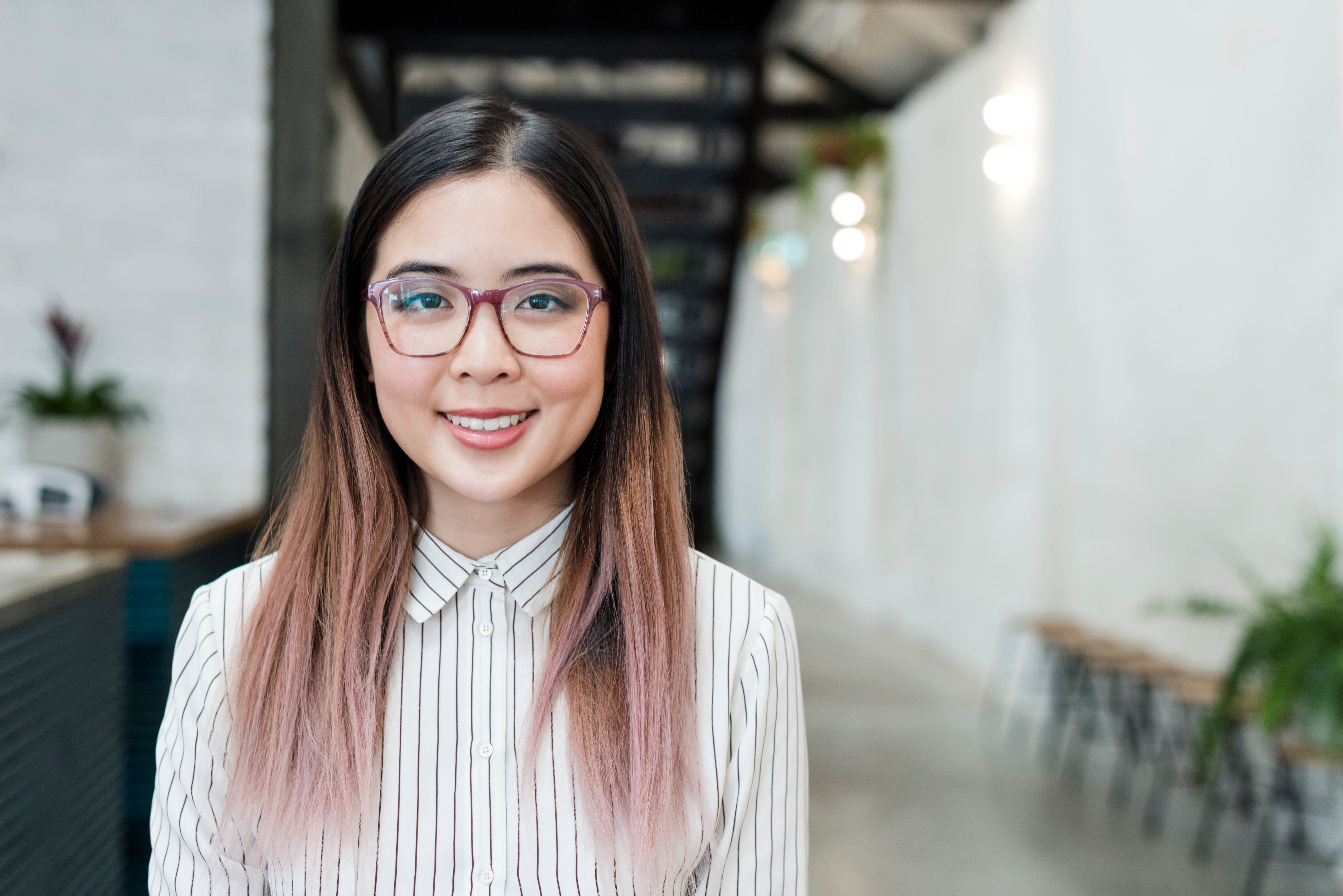 Trendy young Asian businesswoman with pink hair and glassses