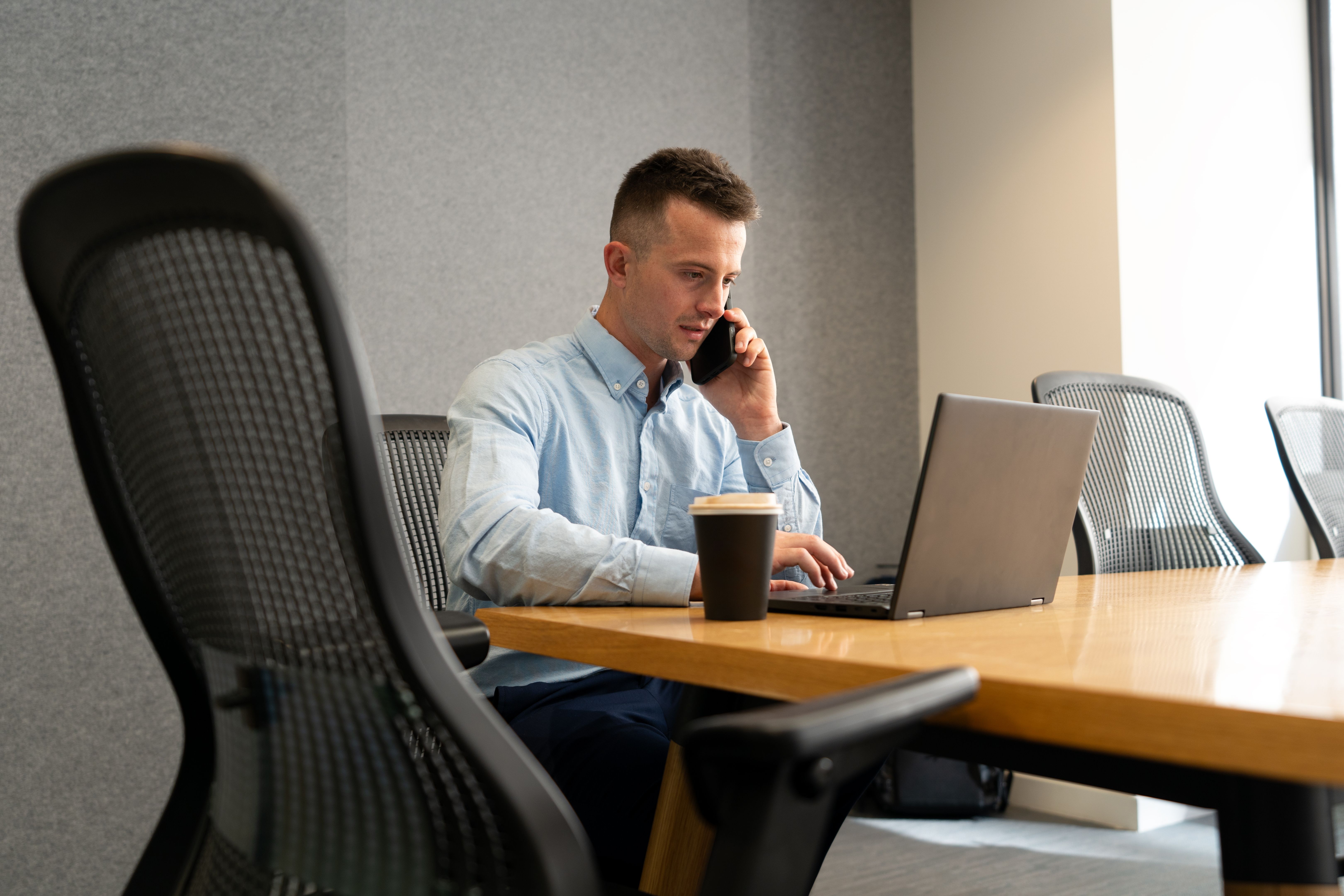 Businessman Taking a Call While Working on Laptop
