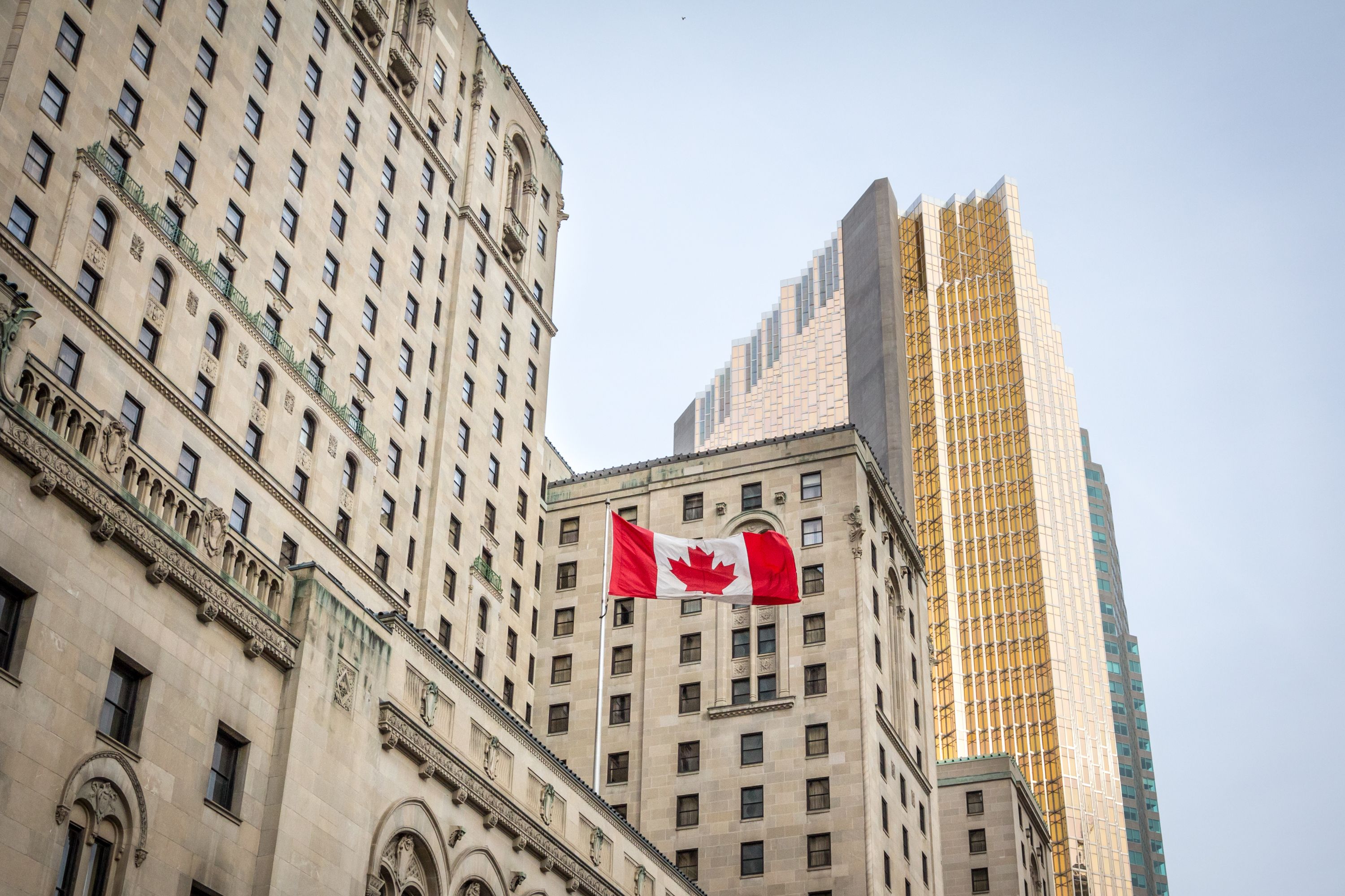 Canadian flag in front of business buildings & older skyscrapers