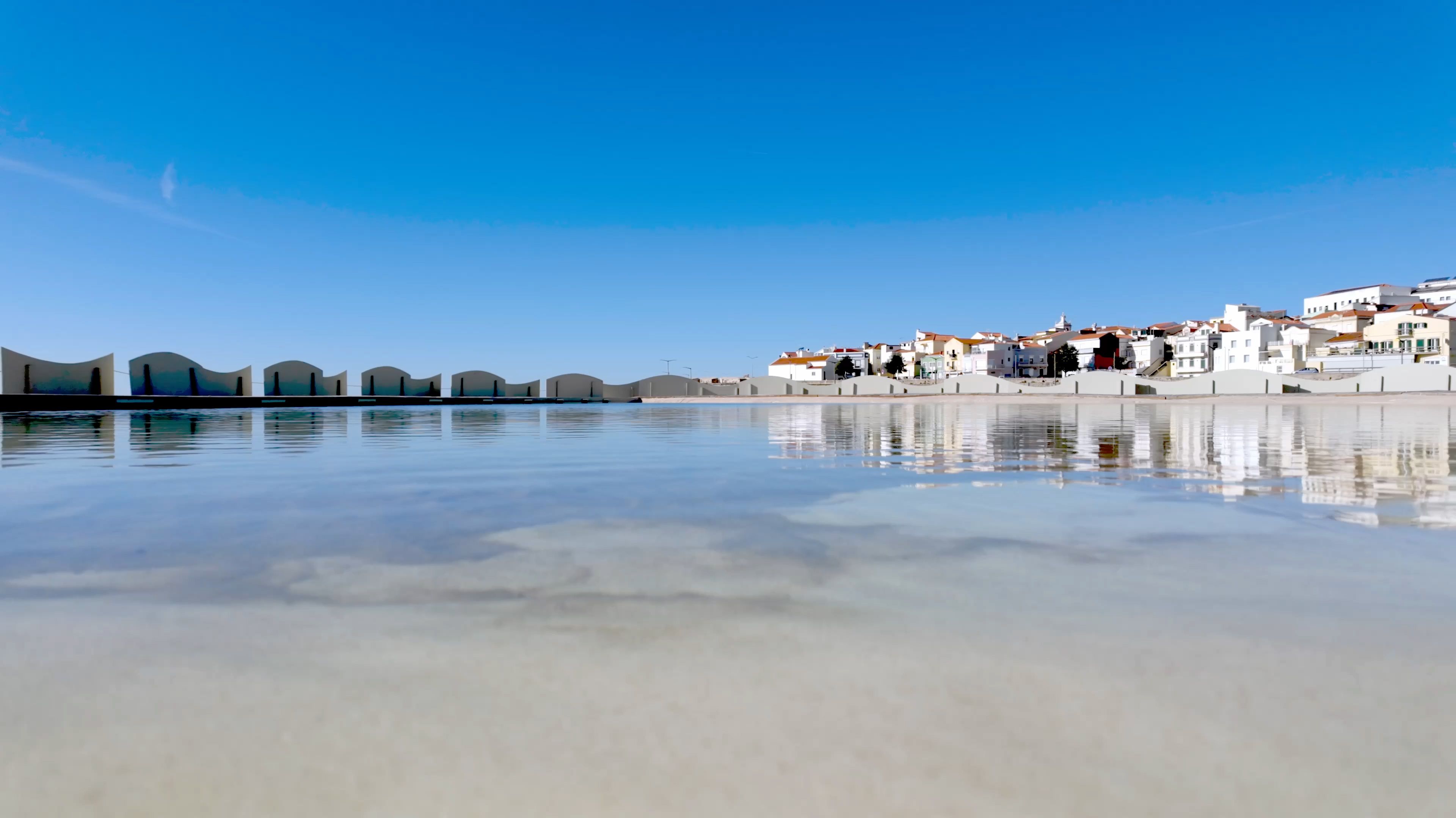 A picturesque coastal town with whitewashed buildings reflects on the calm waters of a lagoon