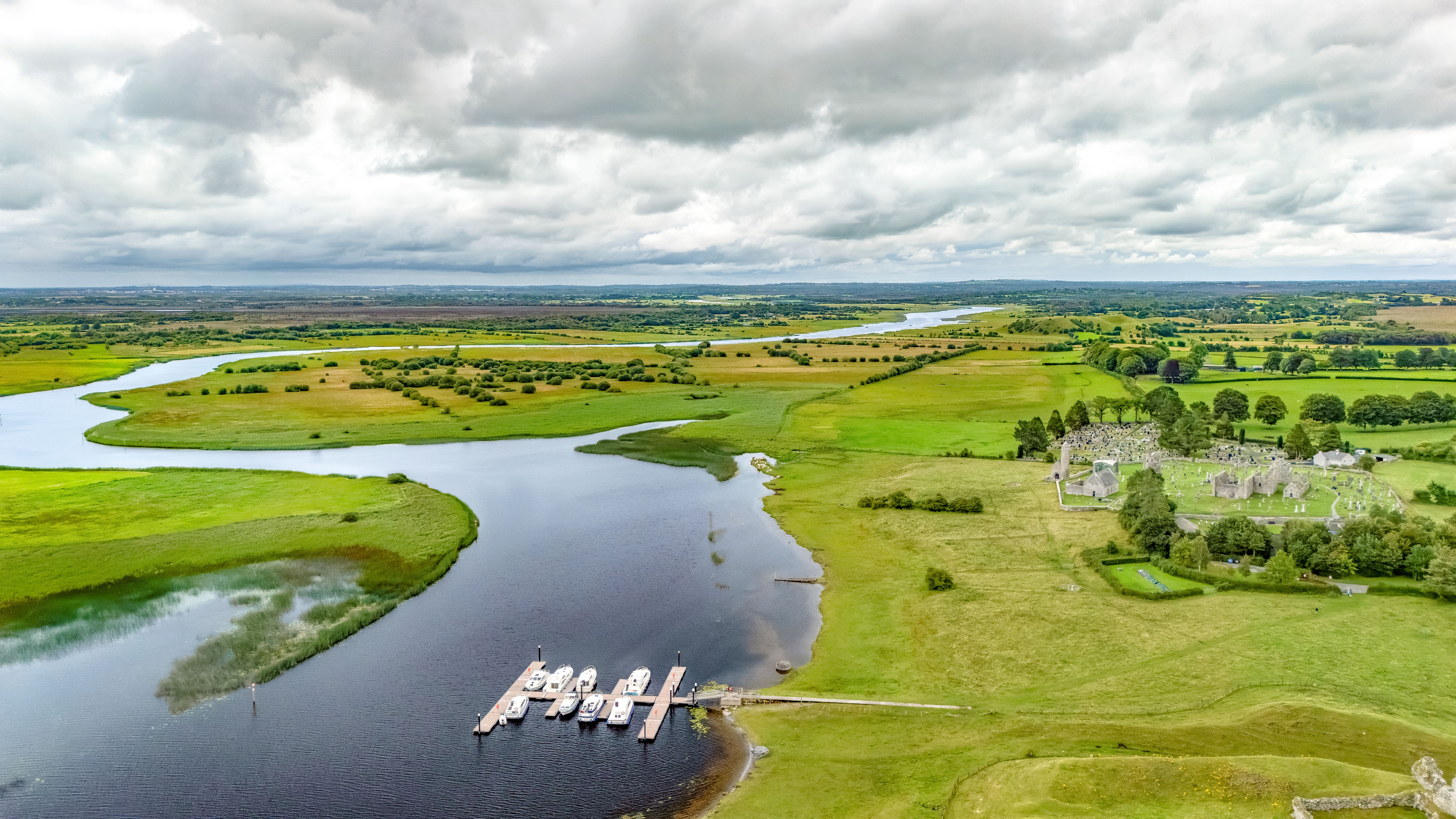 Aerial drone view of Shannon river and countryside rural irish landscape, Clonmacnoise monastery ruins and small marina with vacation river boats, county Offaly, Ireland