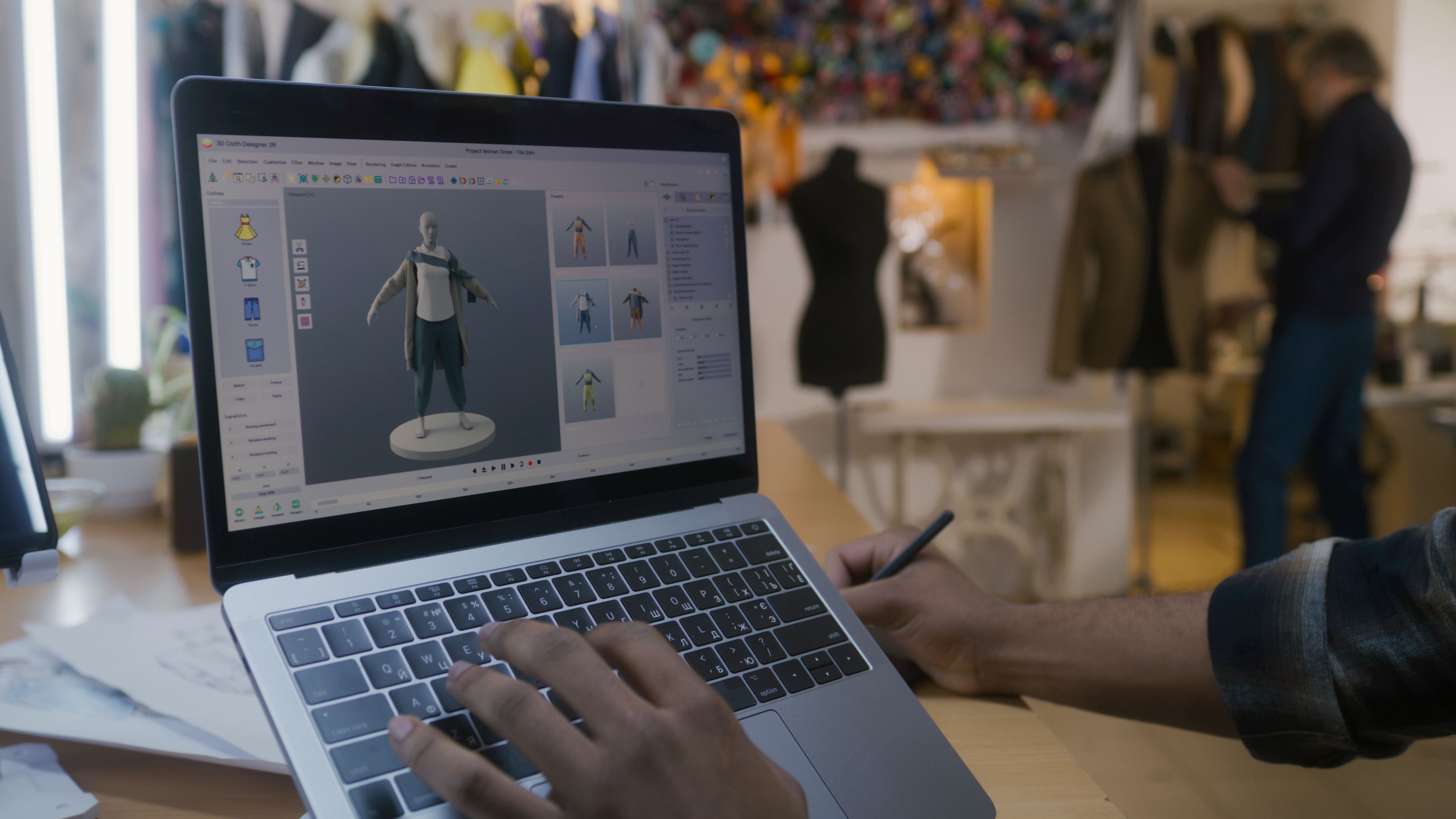 Designer creates 3D clothes on laptop in atelier