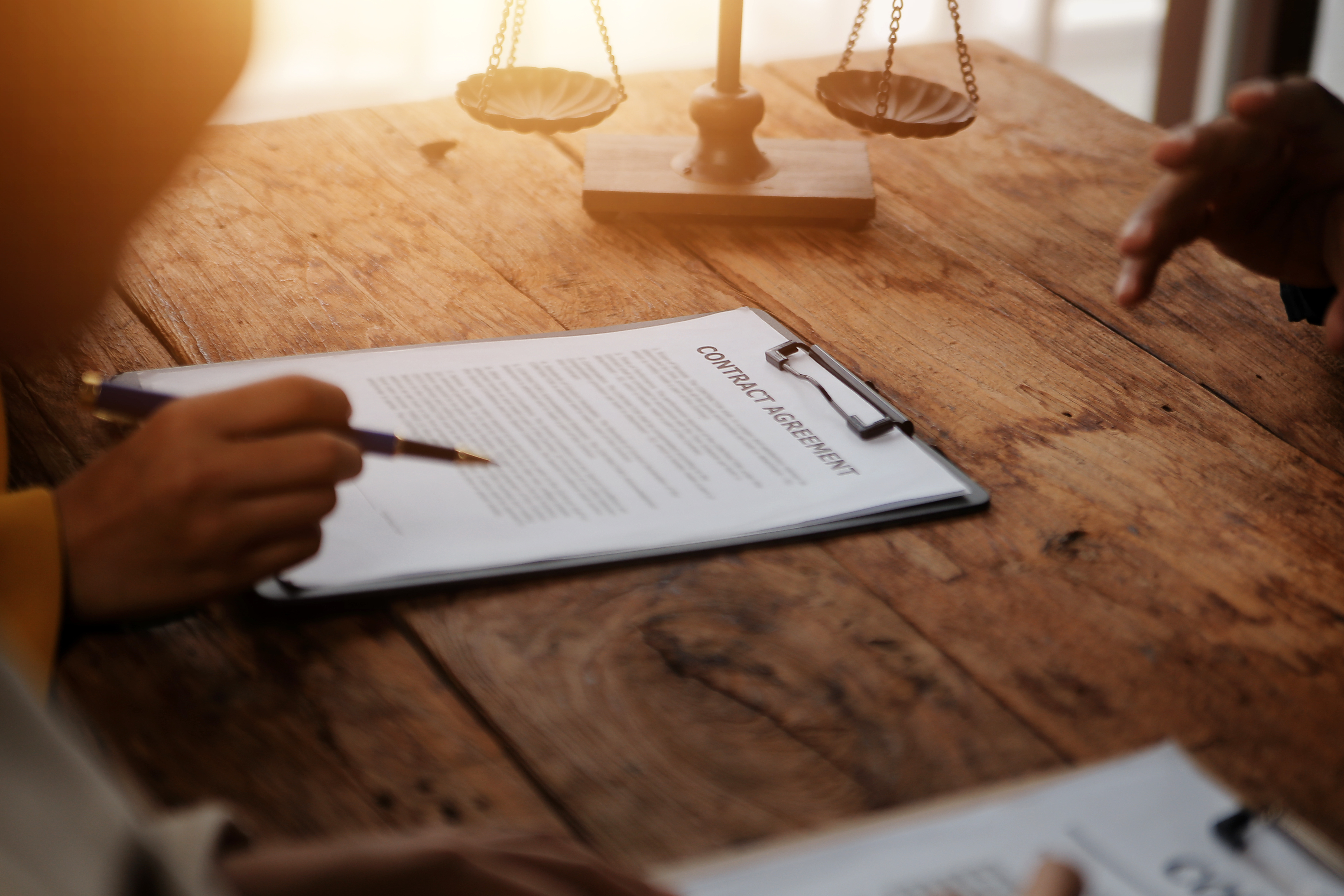 Business and lawyers discussing contract papers with brass scale on desk in office. Law, legal services, advice, justice and law concept picture with film grain effect