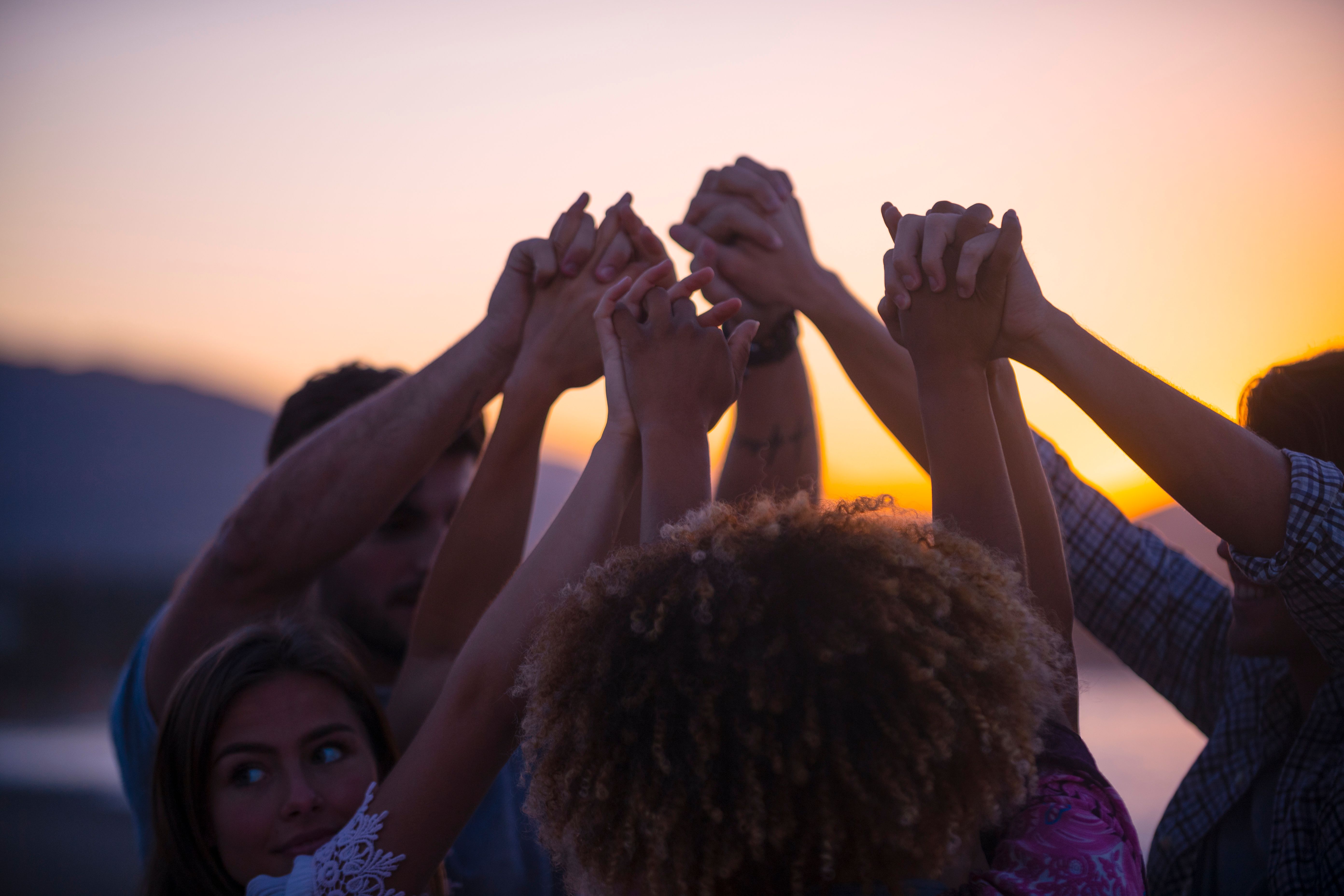 Group of people holding hands in celebration and friendship.