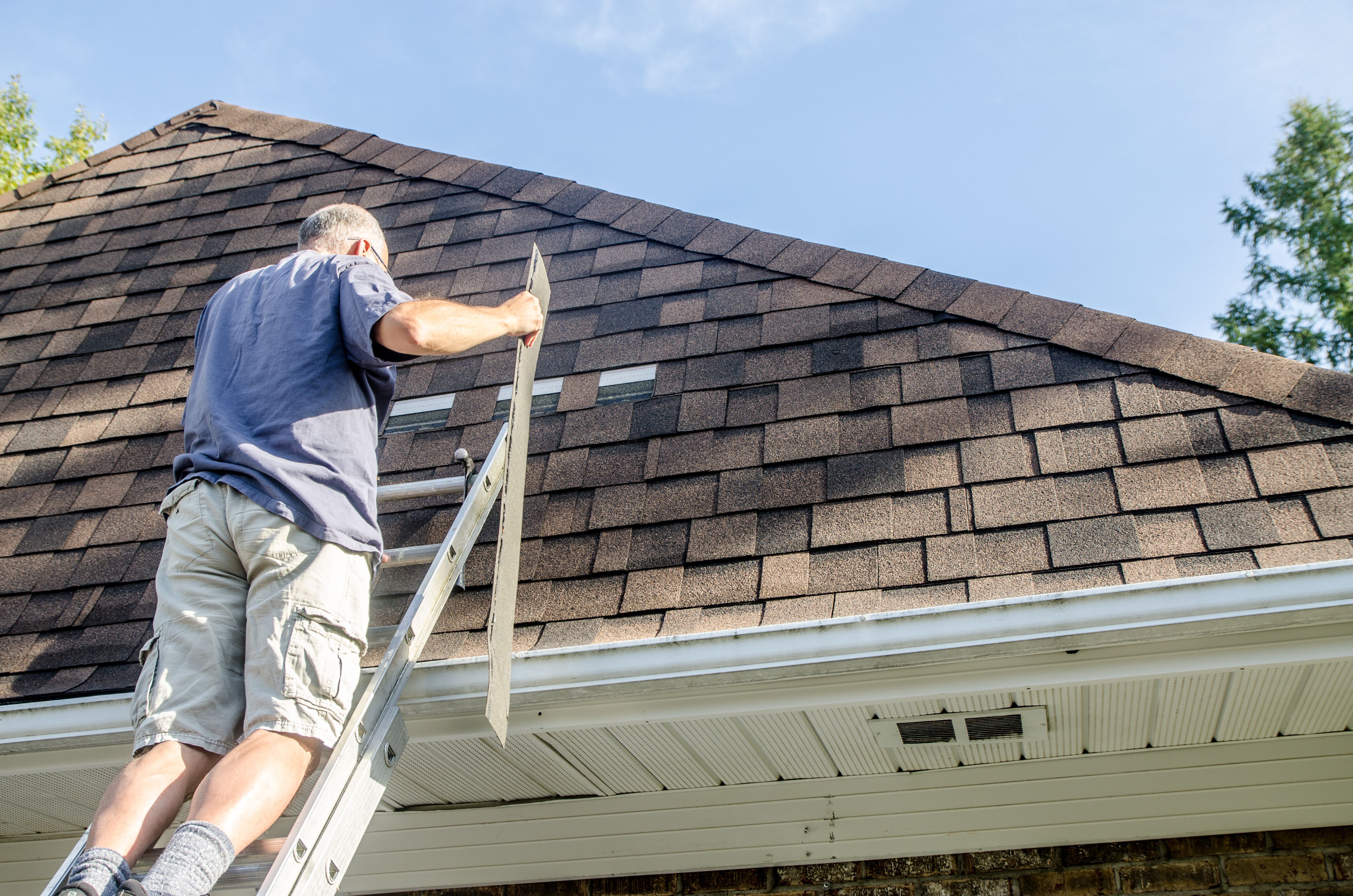 Mature man repairing asphalt shingle roof Mature man repairing asphalt shingle roof