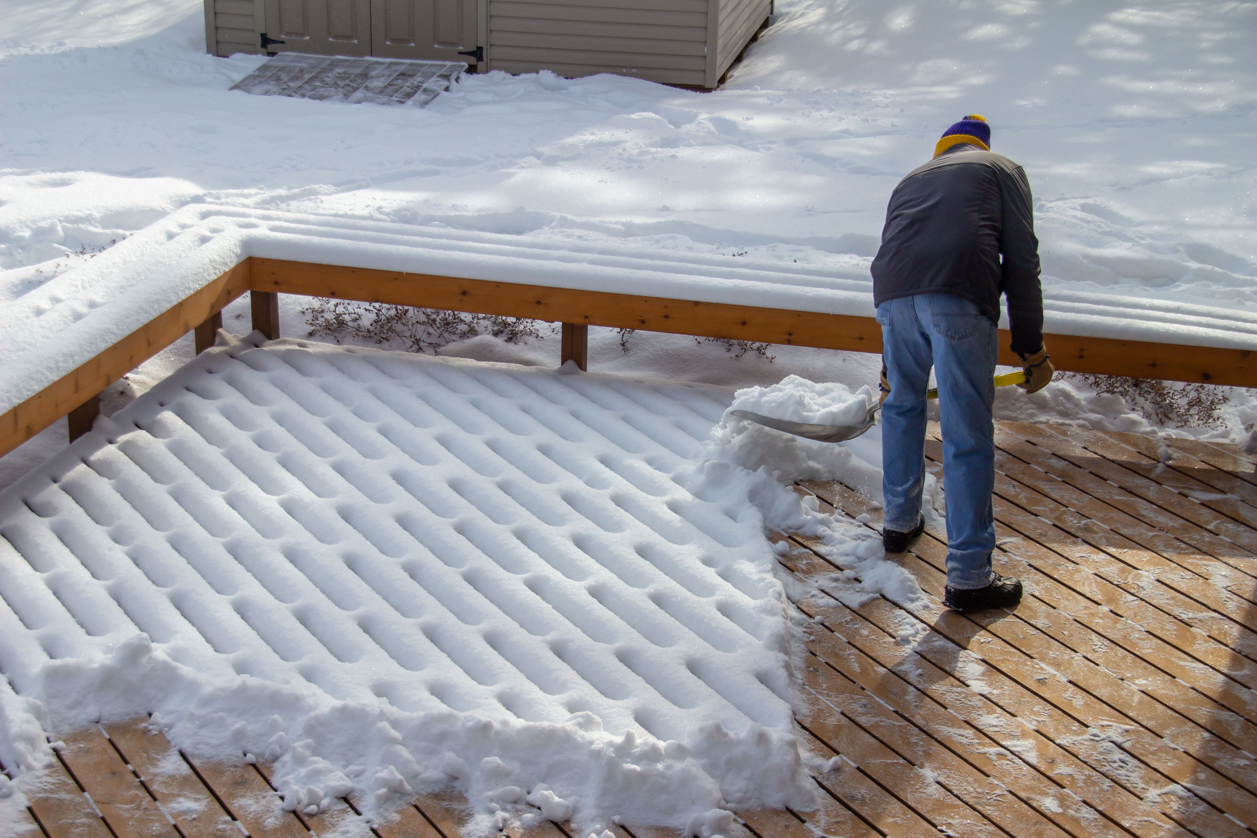 Unrecognizable person shoveling fresh new snow on a deck