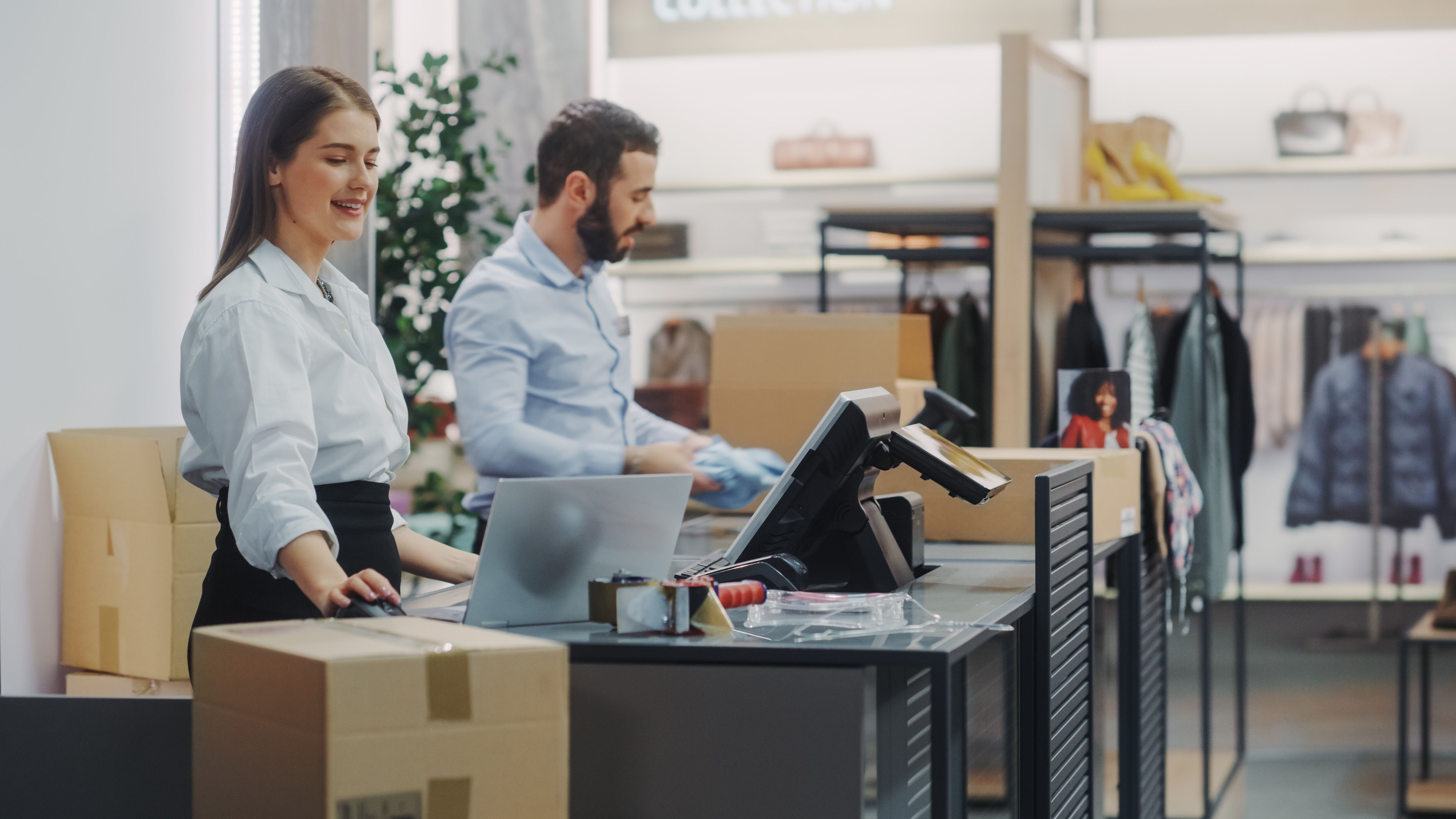 Clothing Store Checkout Cashier Counter: Female and Male Retail Sales Managers Carefully Packing Online Ordered Clothes into Boxes. Fashionable Shop, with Stylish Brand Designs Available on Internet