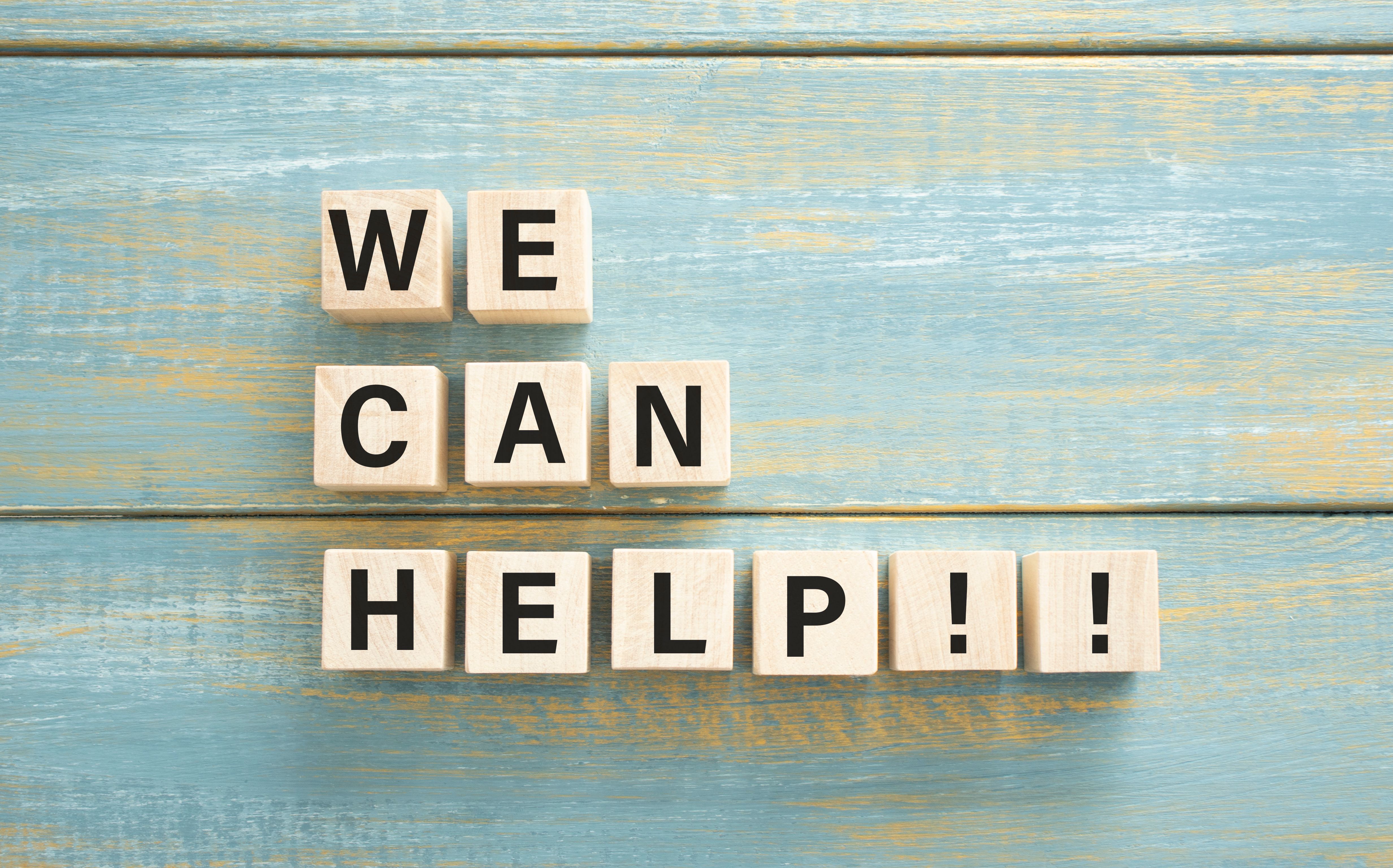 WE CAN HELP text on a wooden cubes on a wooden background.