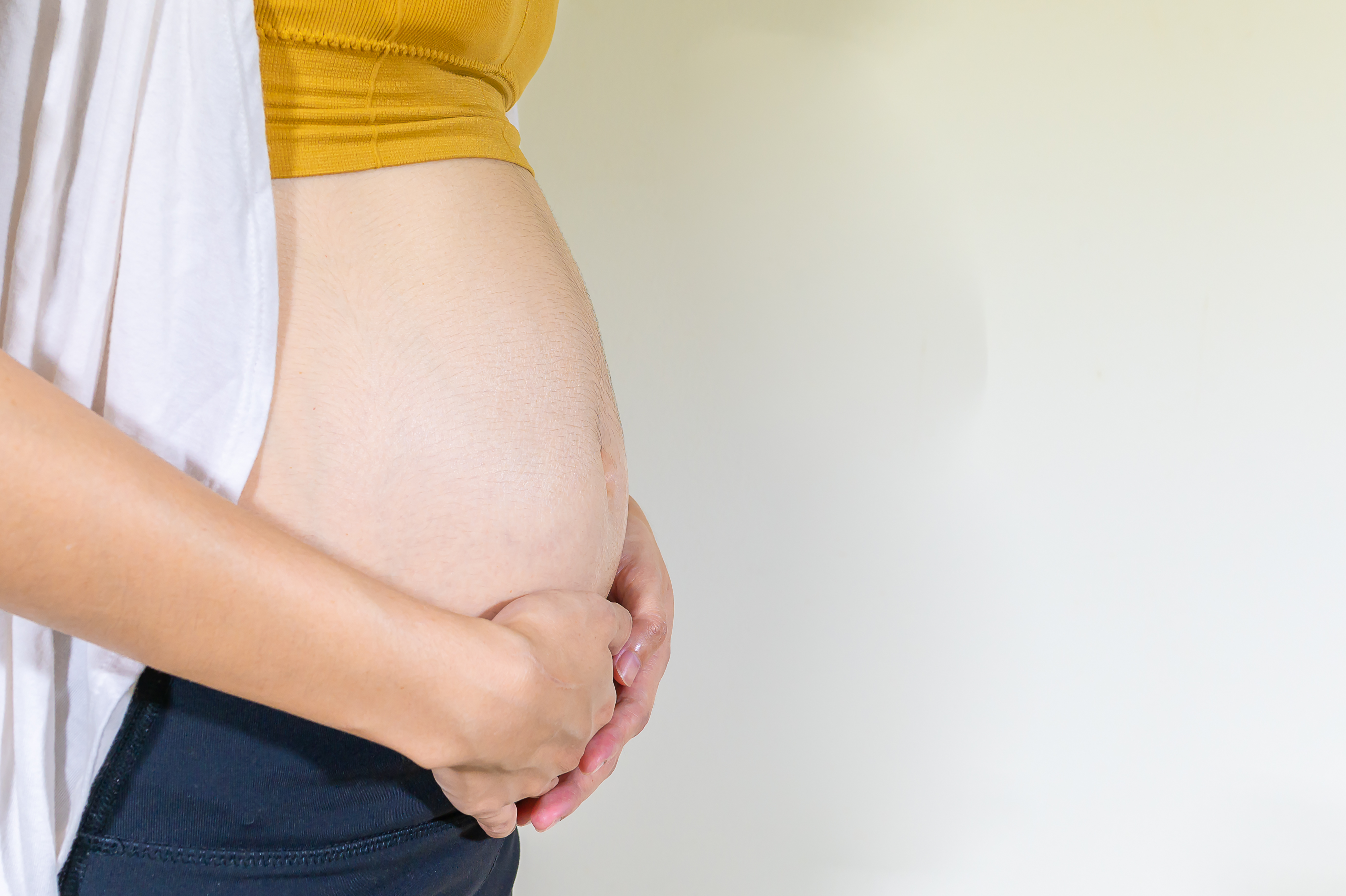 Pregnant woman standing and touching her belly, Second  trimester pregnancy, Mother show love feeling, Baby is loading, Copy space, Close up