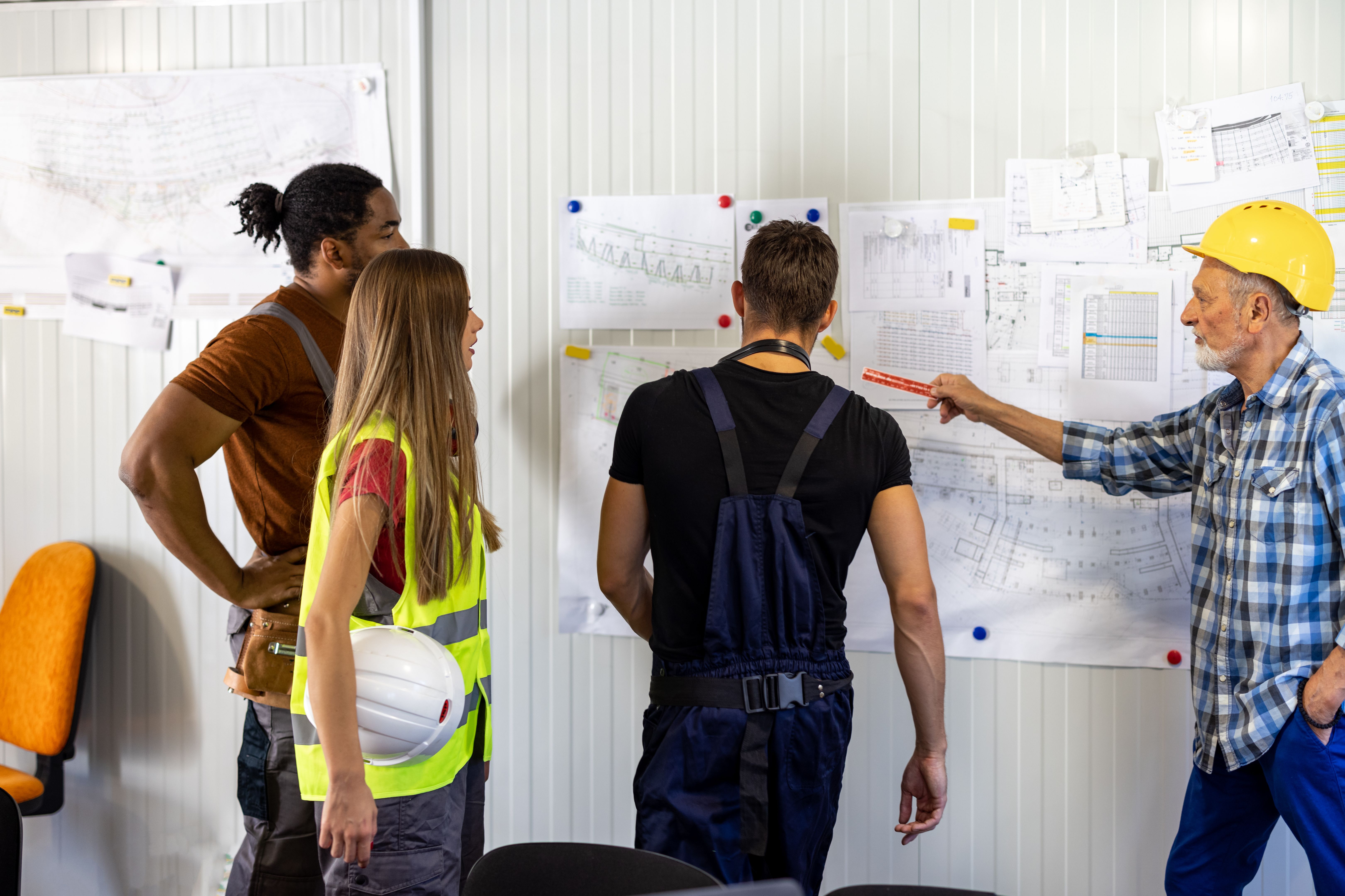 A Senior Construction Worker is Analyzing Project Plans with Young Coworkers.