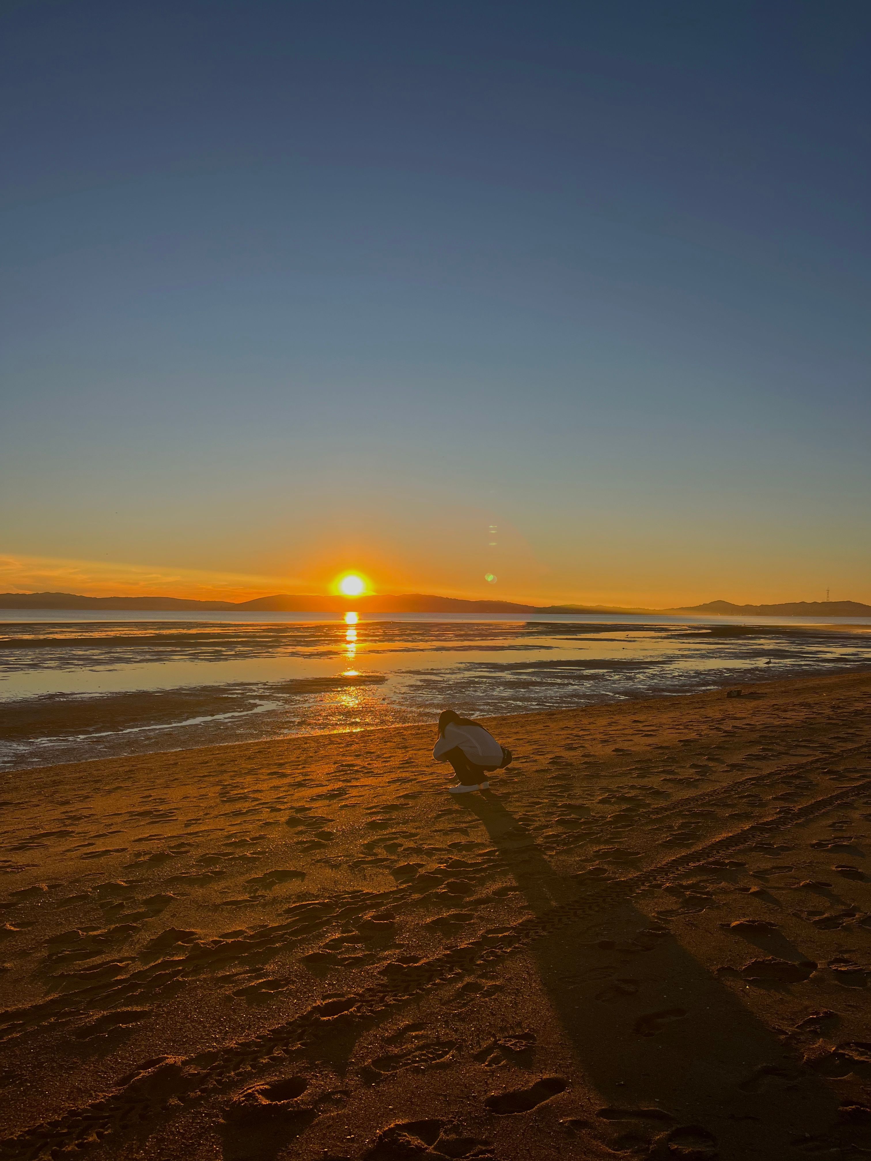 Crouching Person Silhouetted on Beach Sunset