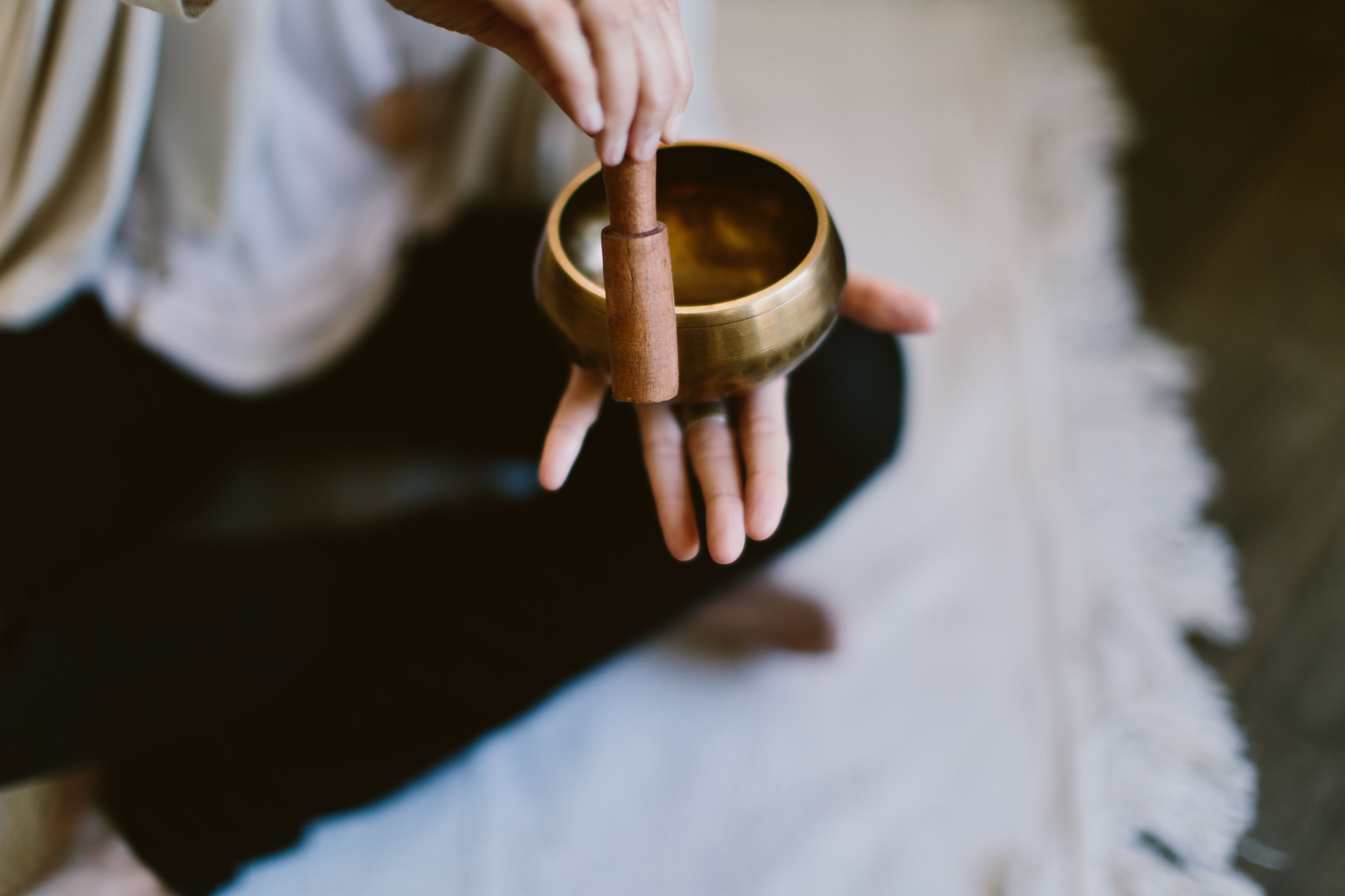 Angle shot of a woman using a Tibetan meditation singing bowl.