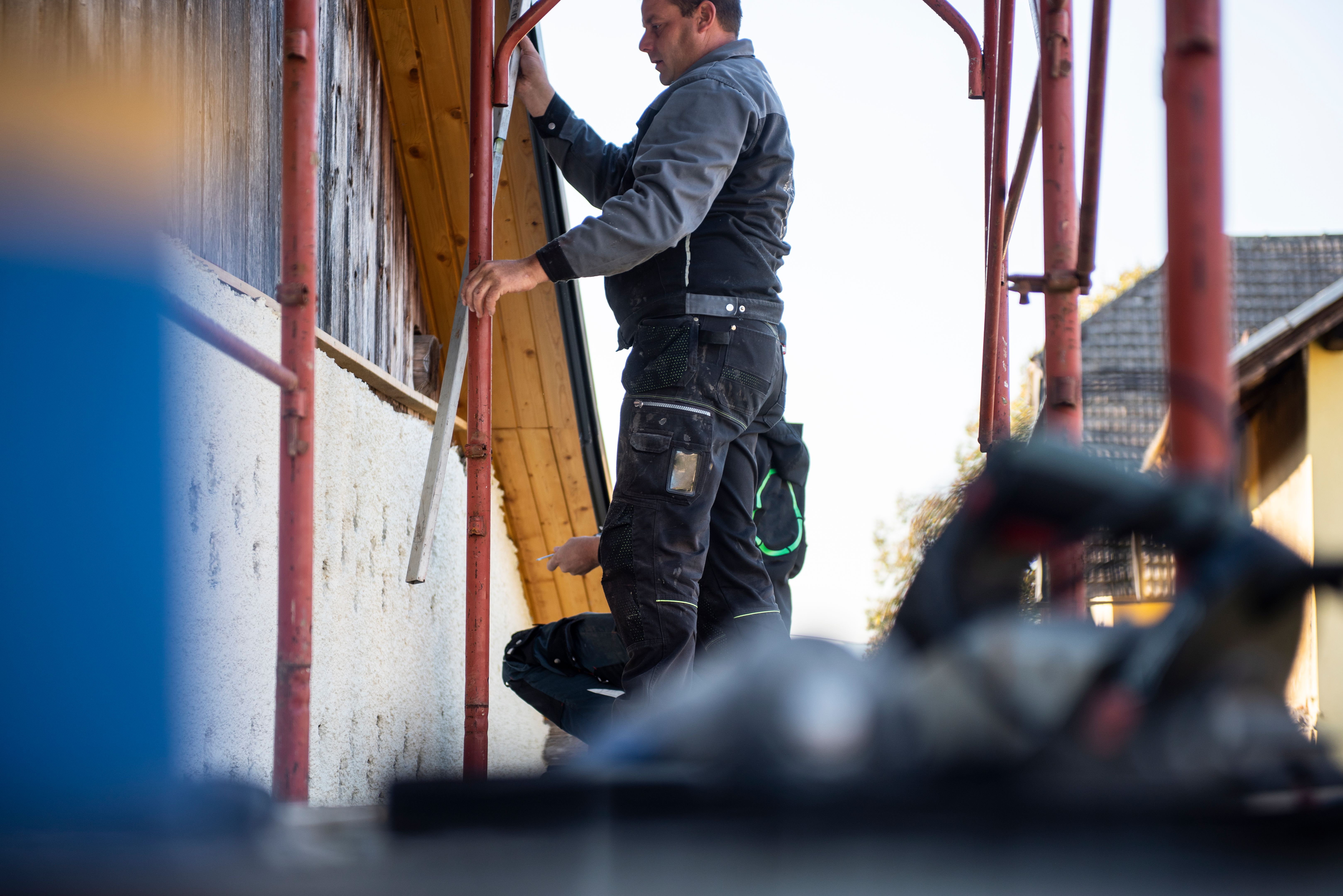 Bauarbeiter installieren Holzplanken an Hausfassade