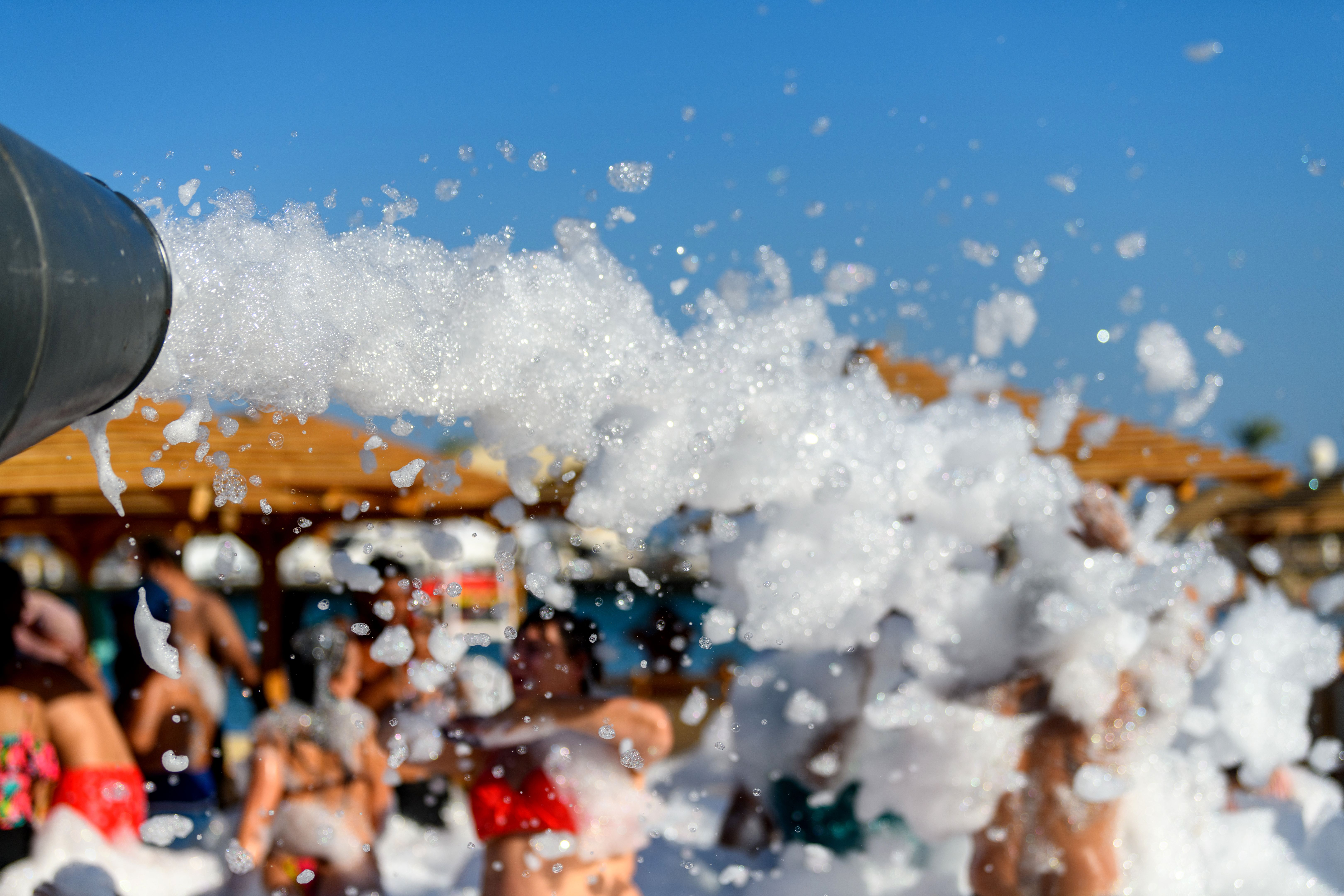 Fun foam party on the beach. Texture foam on a blue sky background
